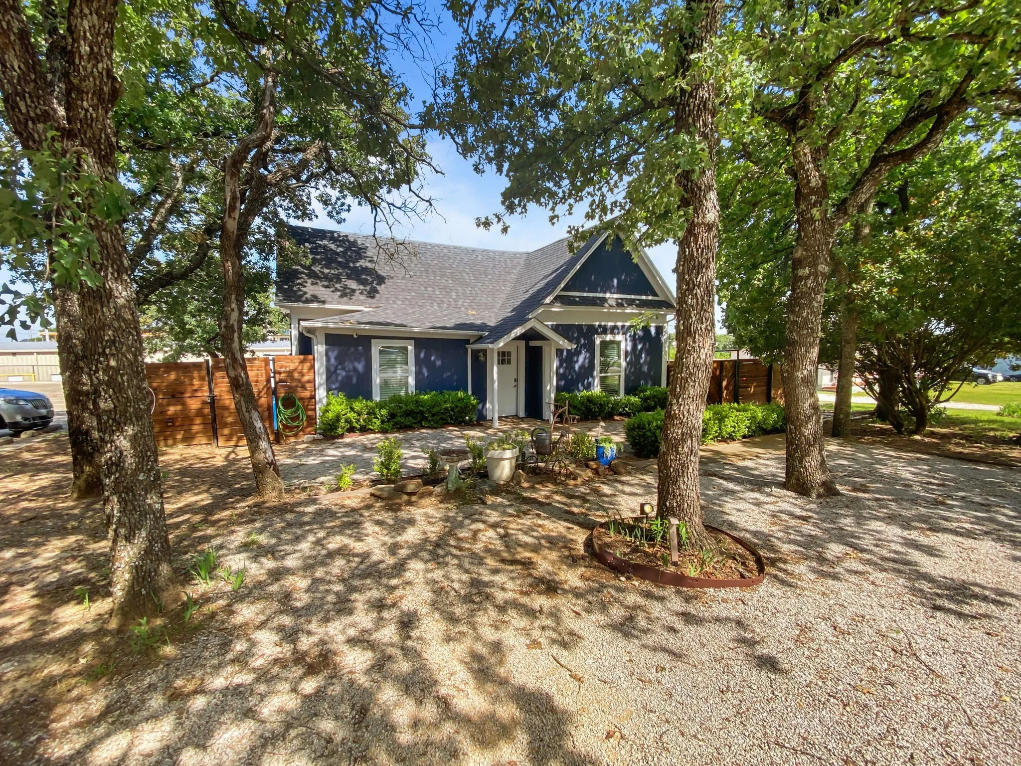 Dark blue siding exterior with white trim, a gabled roof, and a gravel front parking