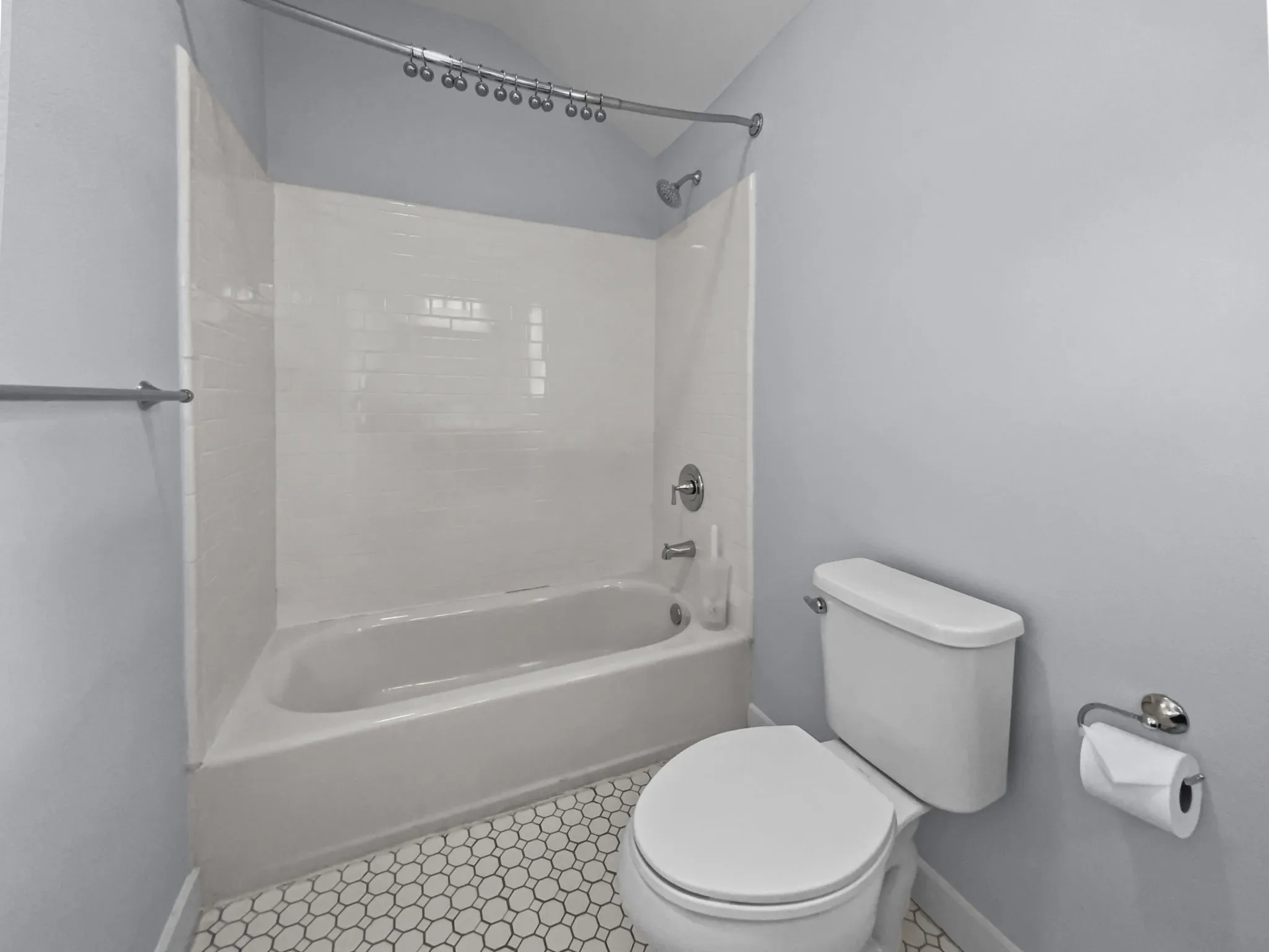Bathtub with white subway tile surround, chrome fixtures, and a curved shower rod