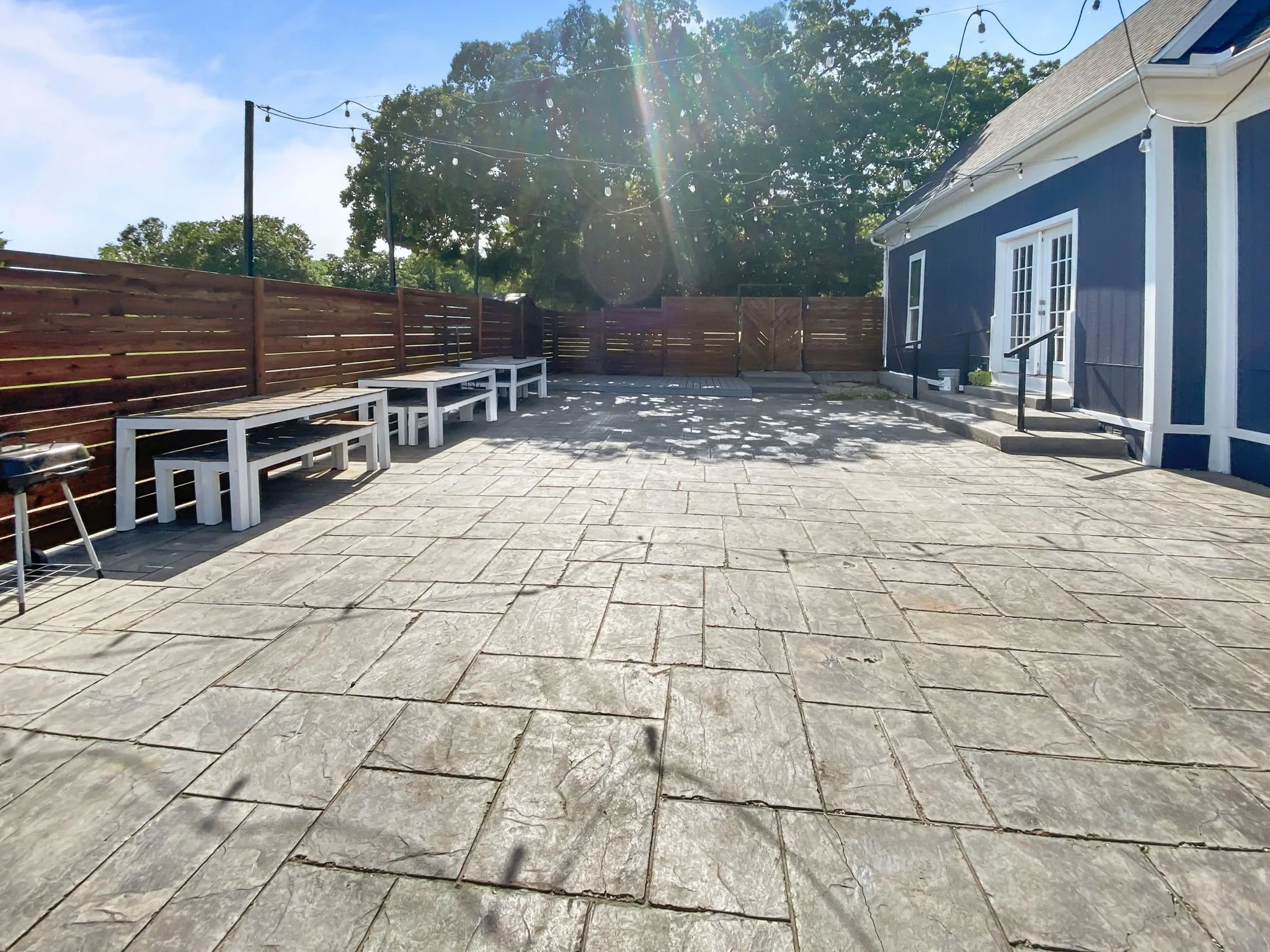 Expansive stamped concrete patio with a dark wood privacy fence,  and a dark blue exterior with white trim