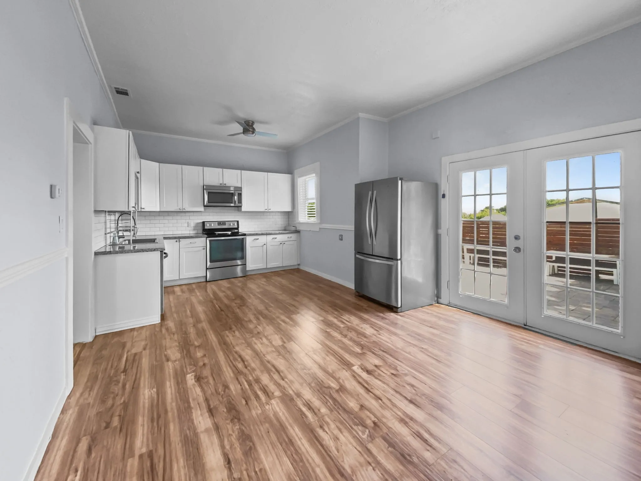 Kitchen featuring wood-finish flooring, white cabinetry, stainless steel appliances, and a subway tile backsplash