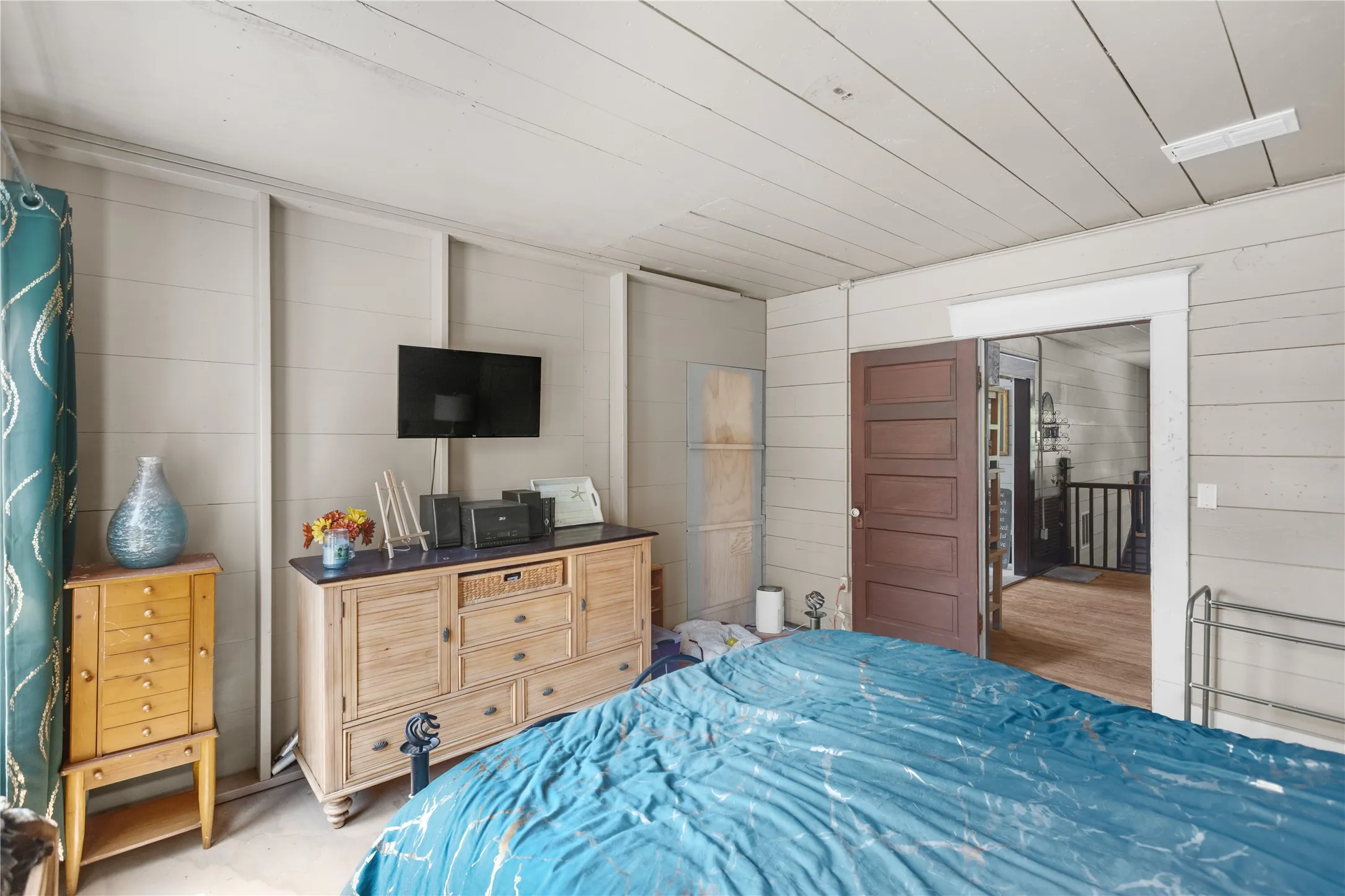 Shiplap walls and ceiling, wood-finish flooring, and a paneled interior door