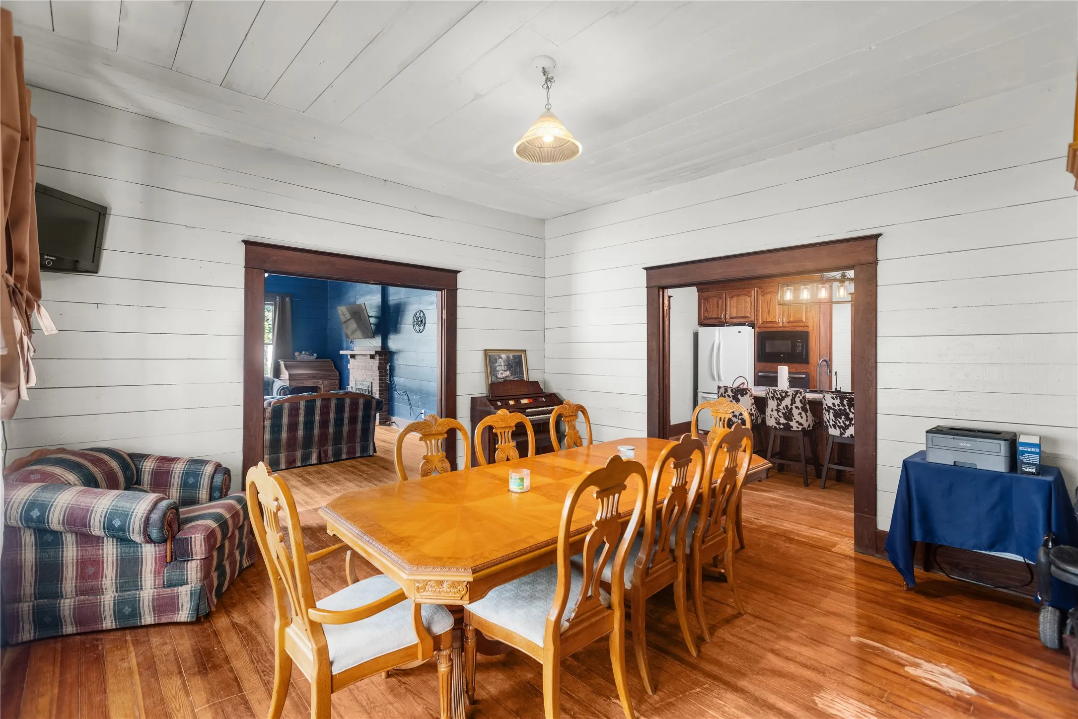 Original hardwood flooring, white shiplap walls, dark wood trim, and a built-in kitchen pass-through with pendant lighting