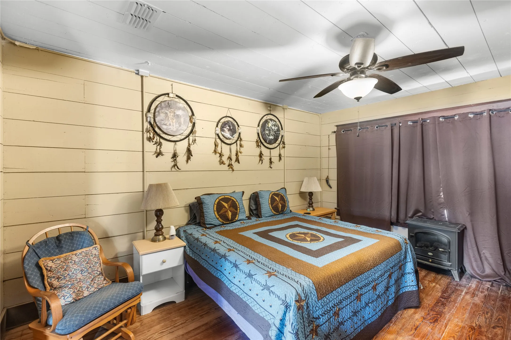 Wood-finish flooring, paneled walls, ceiling fan with integrated lighting, and a built-in fireplace