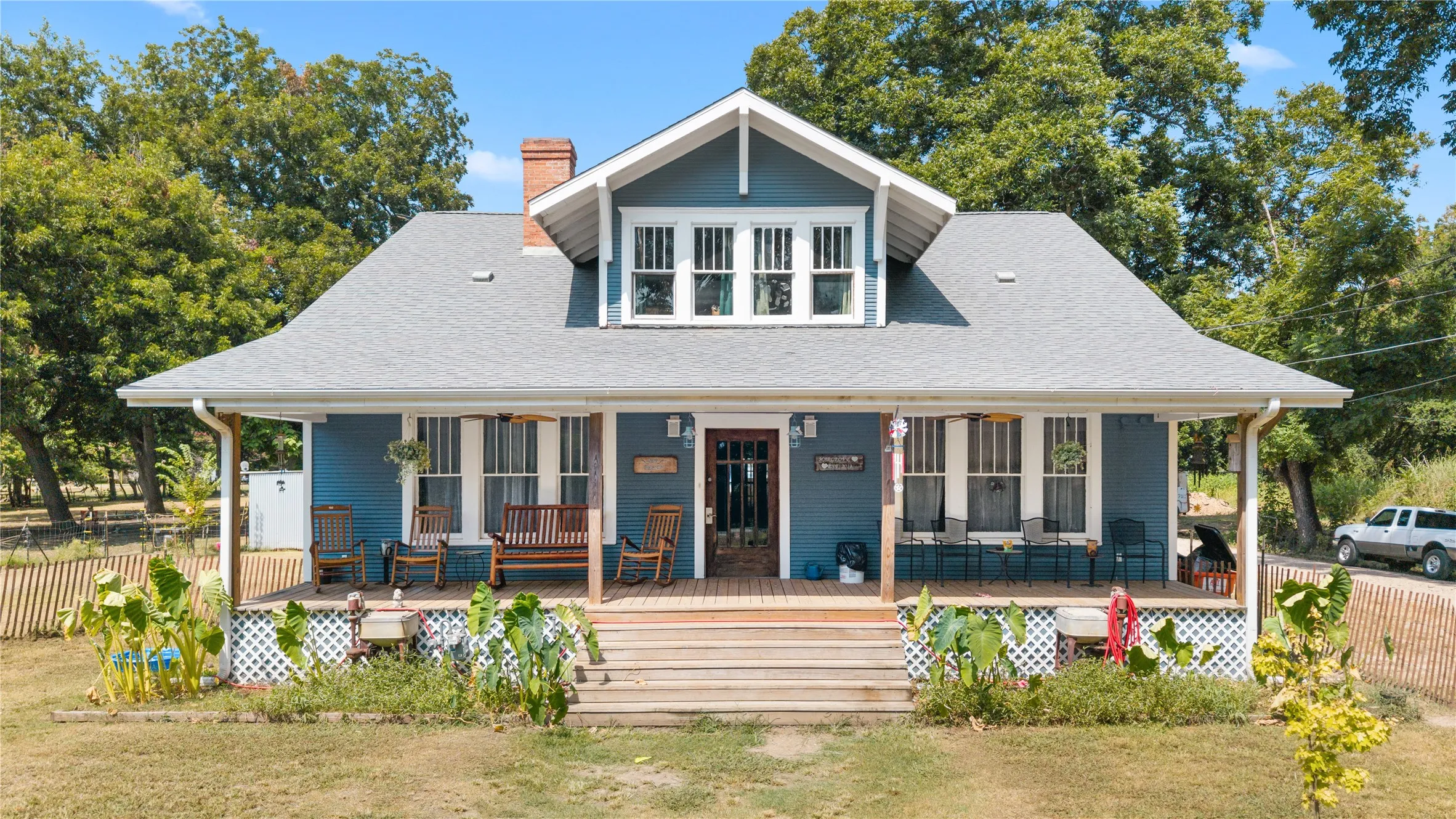 Front exterior featuring a covered porch, wood plank decking, and a dormer window
