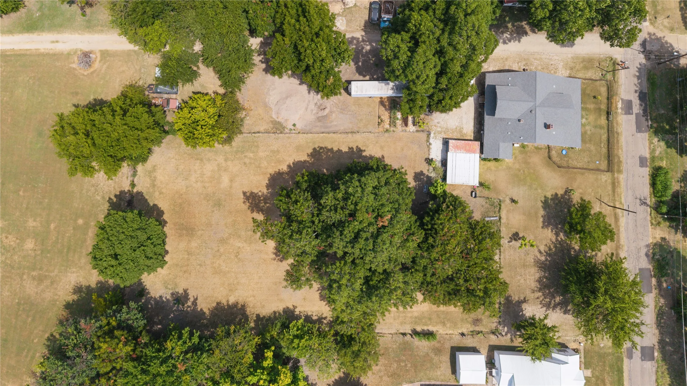 Aerial perspective highlighting the property's expansive lot, mature trees, and detached outbuilding
