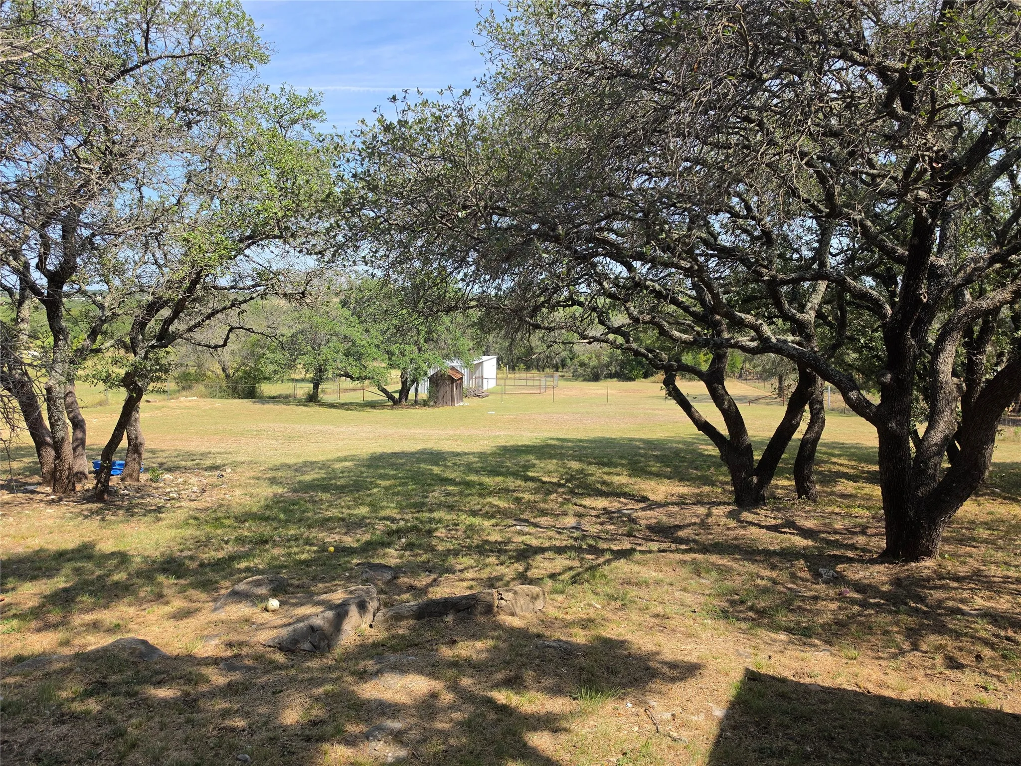 Expansive outdoor space featuring a natural landscape, mature trees, and an accessory structure