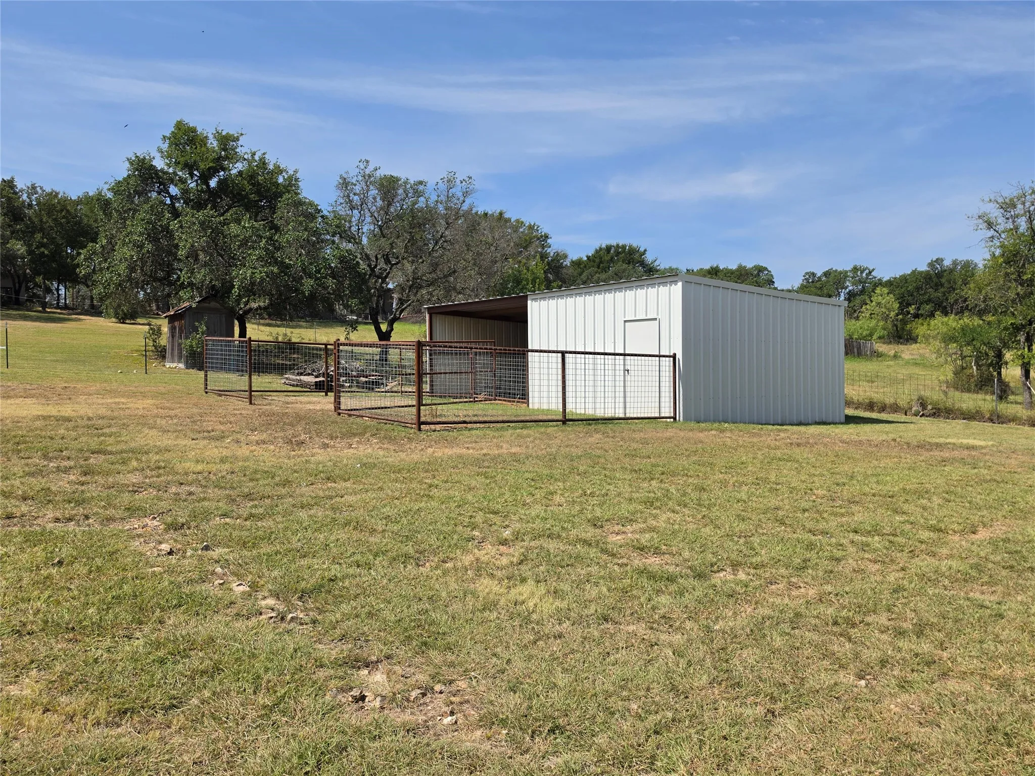 Metal-sided outbuilding with an attached covered area and fenced enclosures