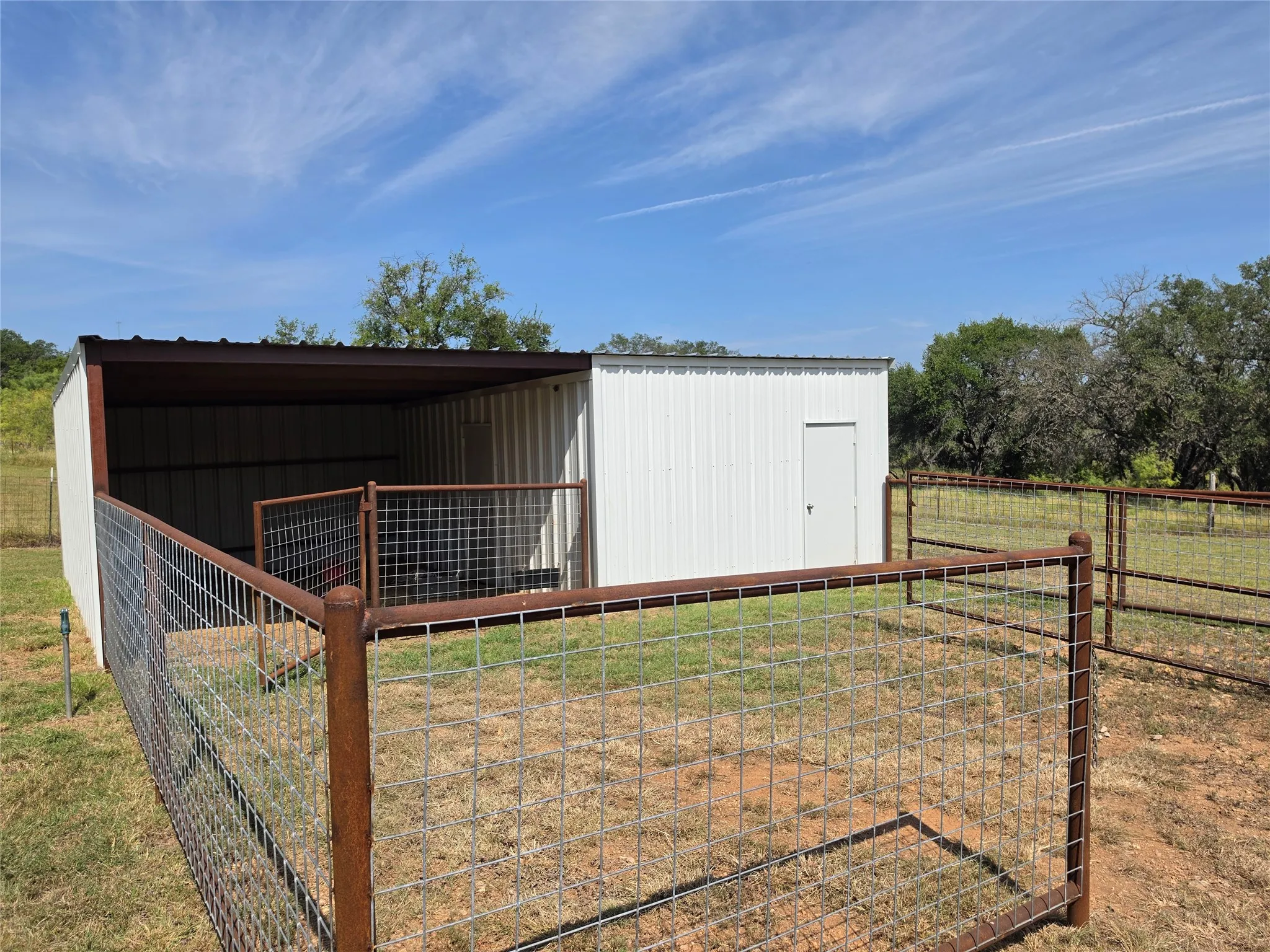Metal outbuilding with covered shelter and enclosed pen
