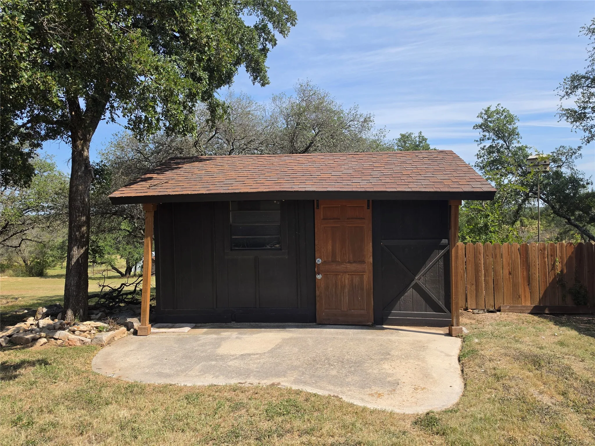 Detached accessory structure featuring a brown shingle roof and a concrete pad