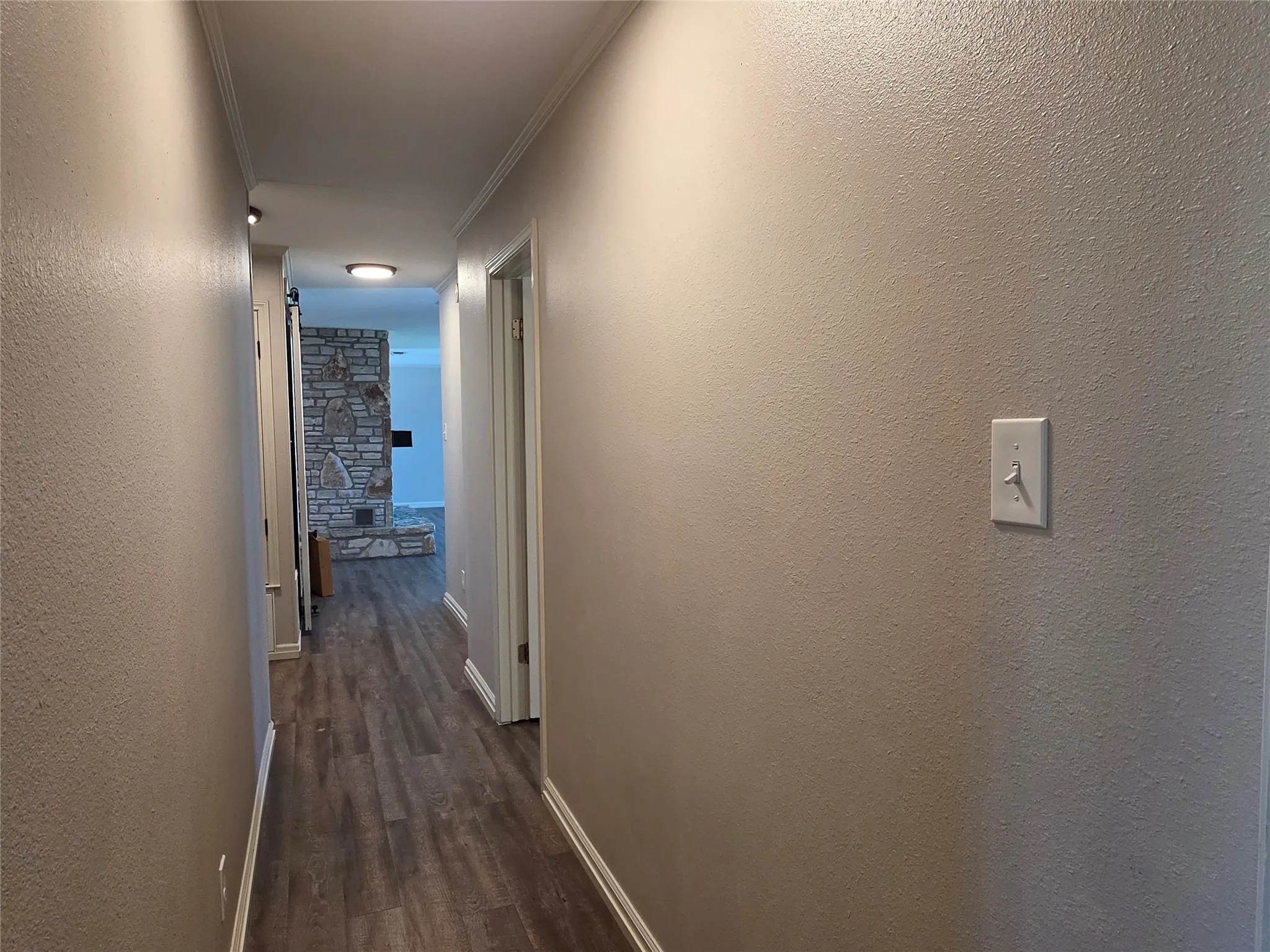 Hallway featuring wood-finish flooring and crown molding