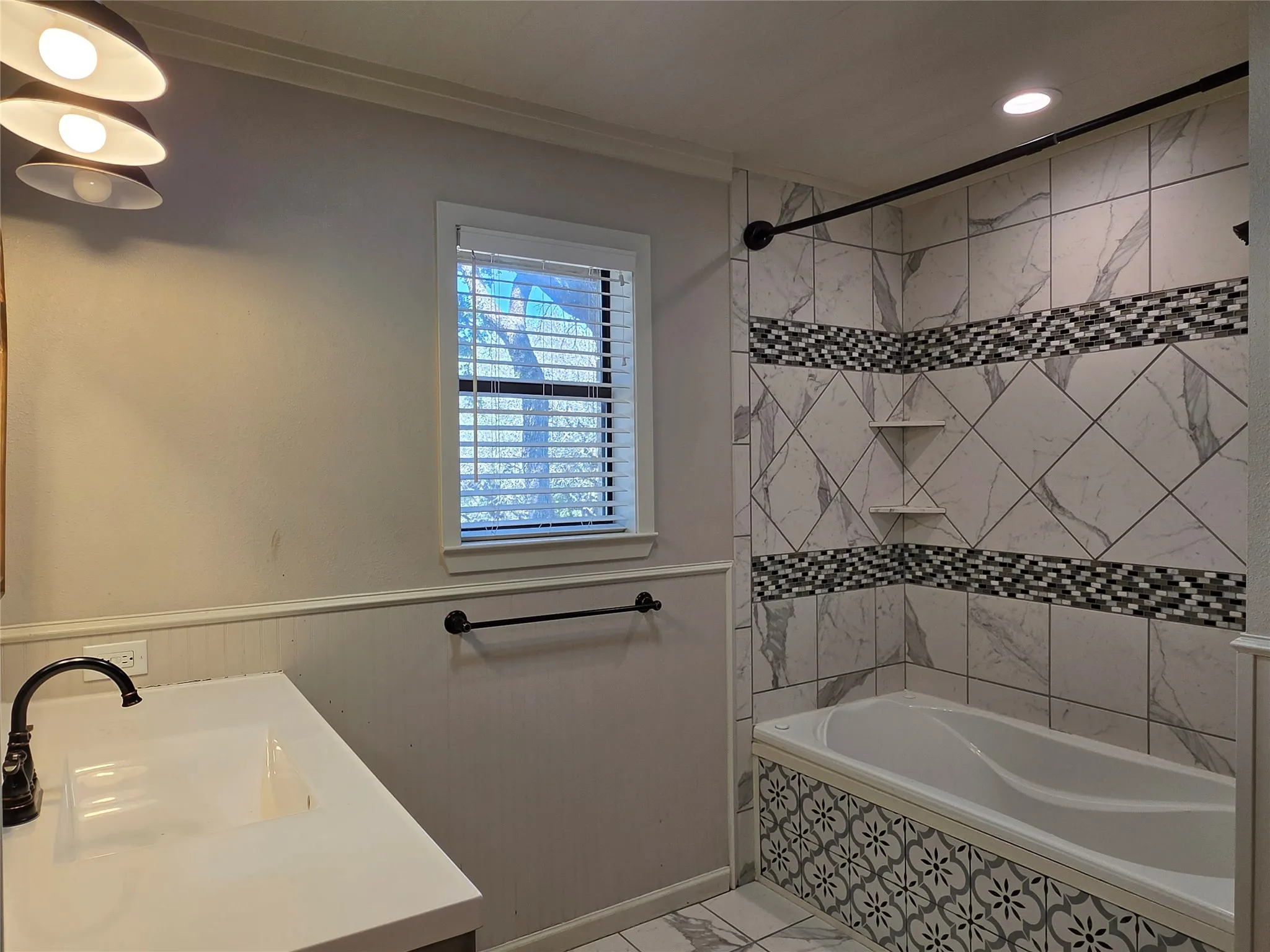 Tiled tub/shower combination with decorative accent bands and built-in shelving