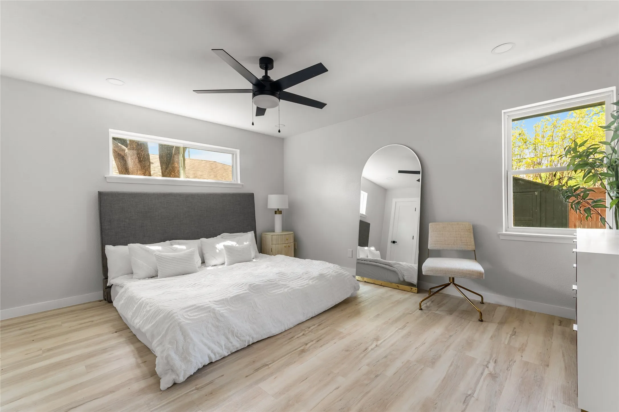Light wood-finish flooring with a ceiling fan, recessed lighting, and large windows