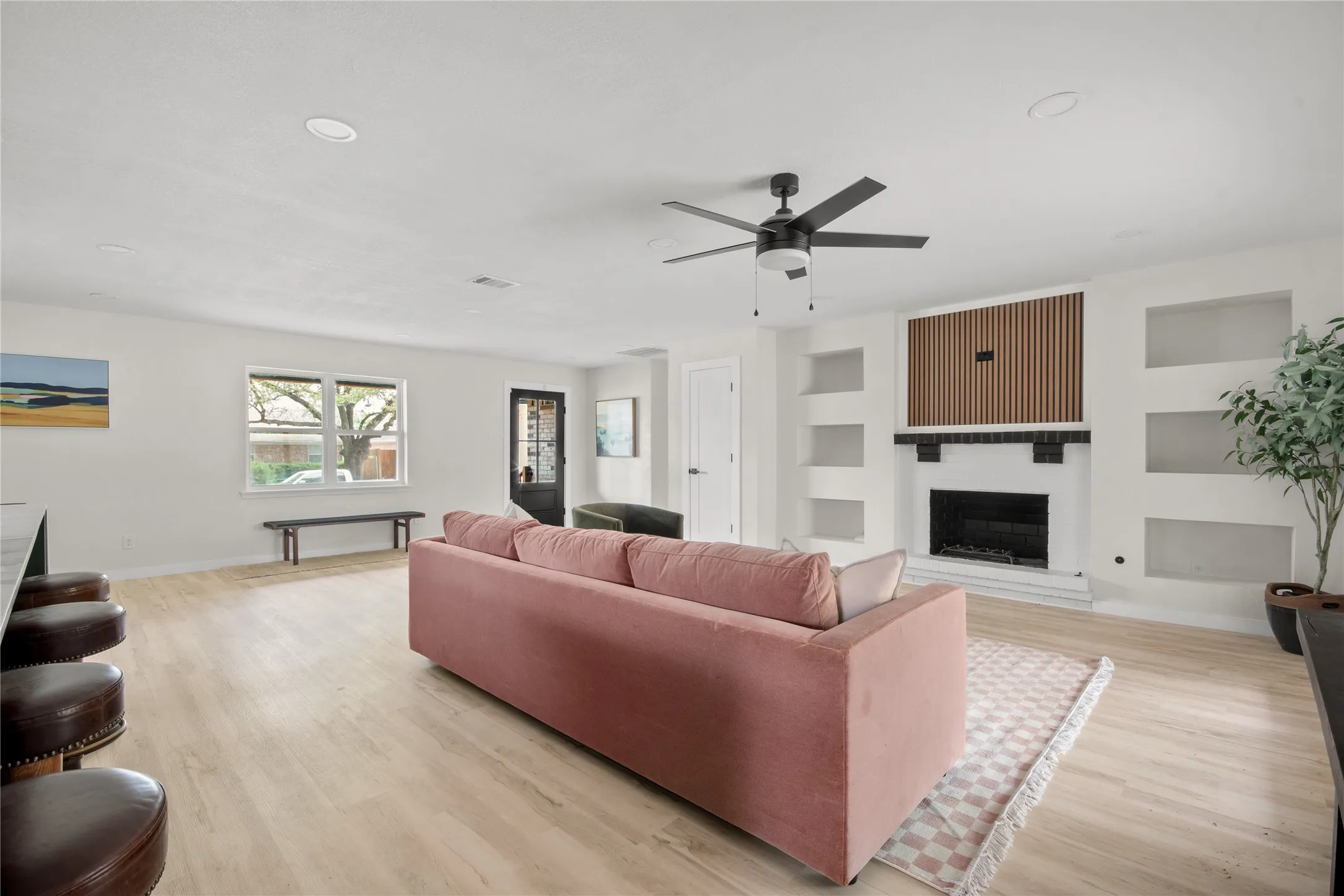 Recessed lighting, wood-finish flooring, ceiling fan, built-in shelving, and a fireplace with a wood mantel
