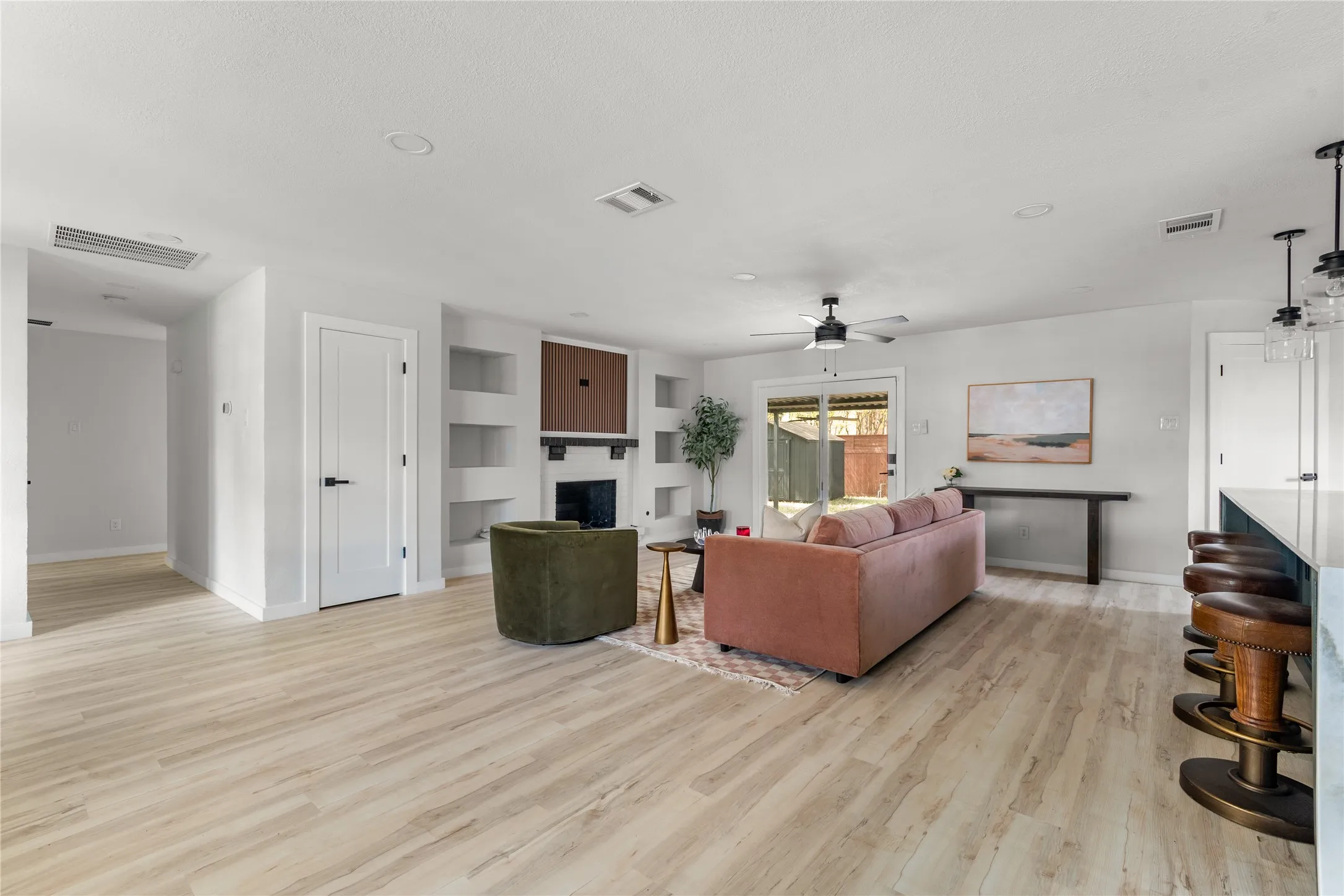 Spacious living area featuring wood-finish flooring, recessed lighting, and a built-in fireplace with shelving