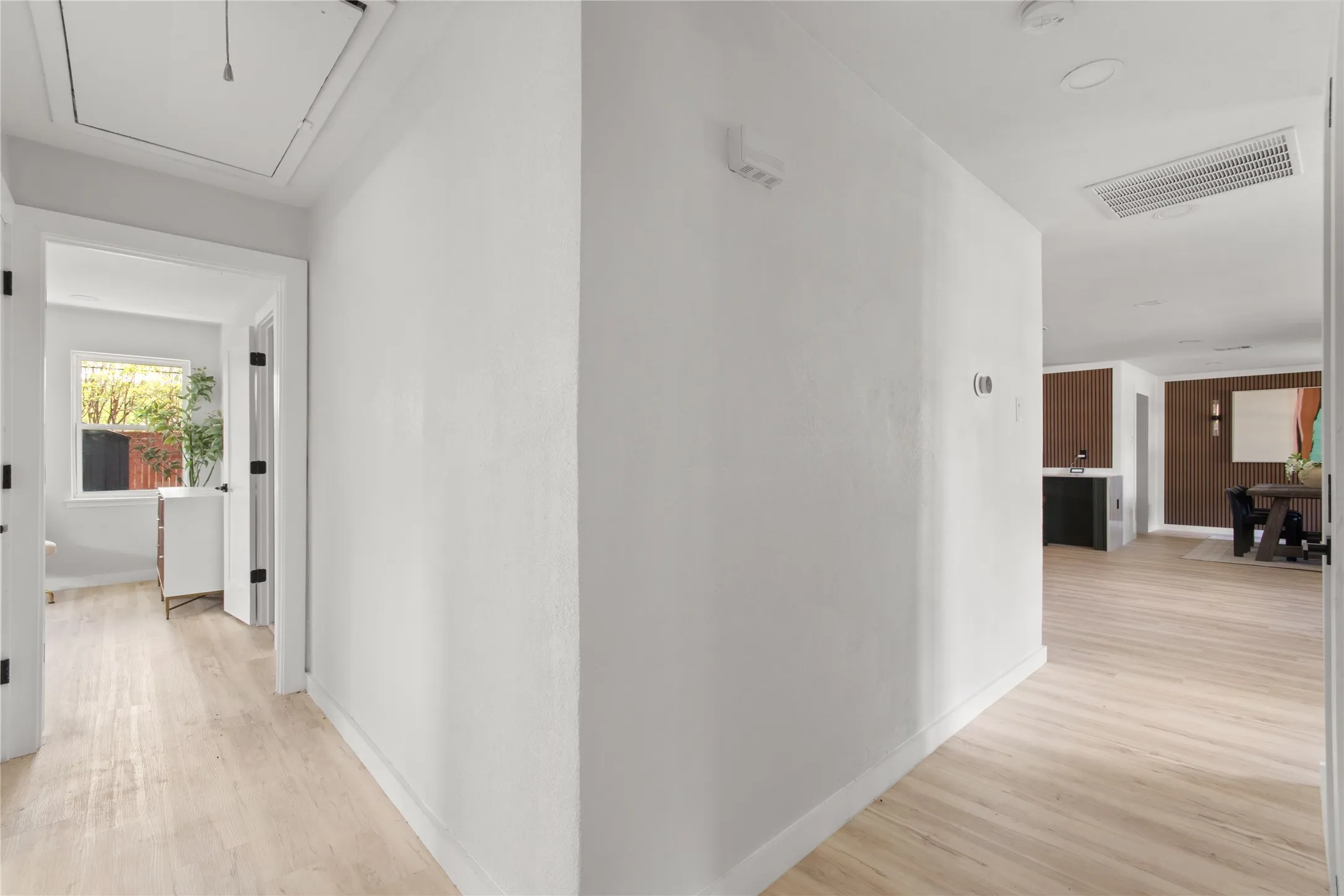 Light wood-finish flooring throughout, white painted walls, and black door hardware