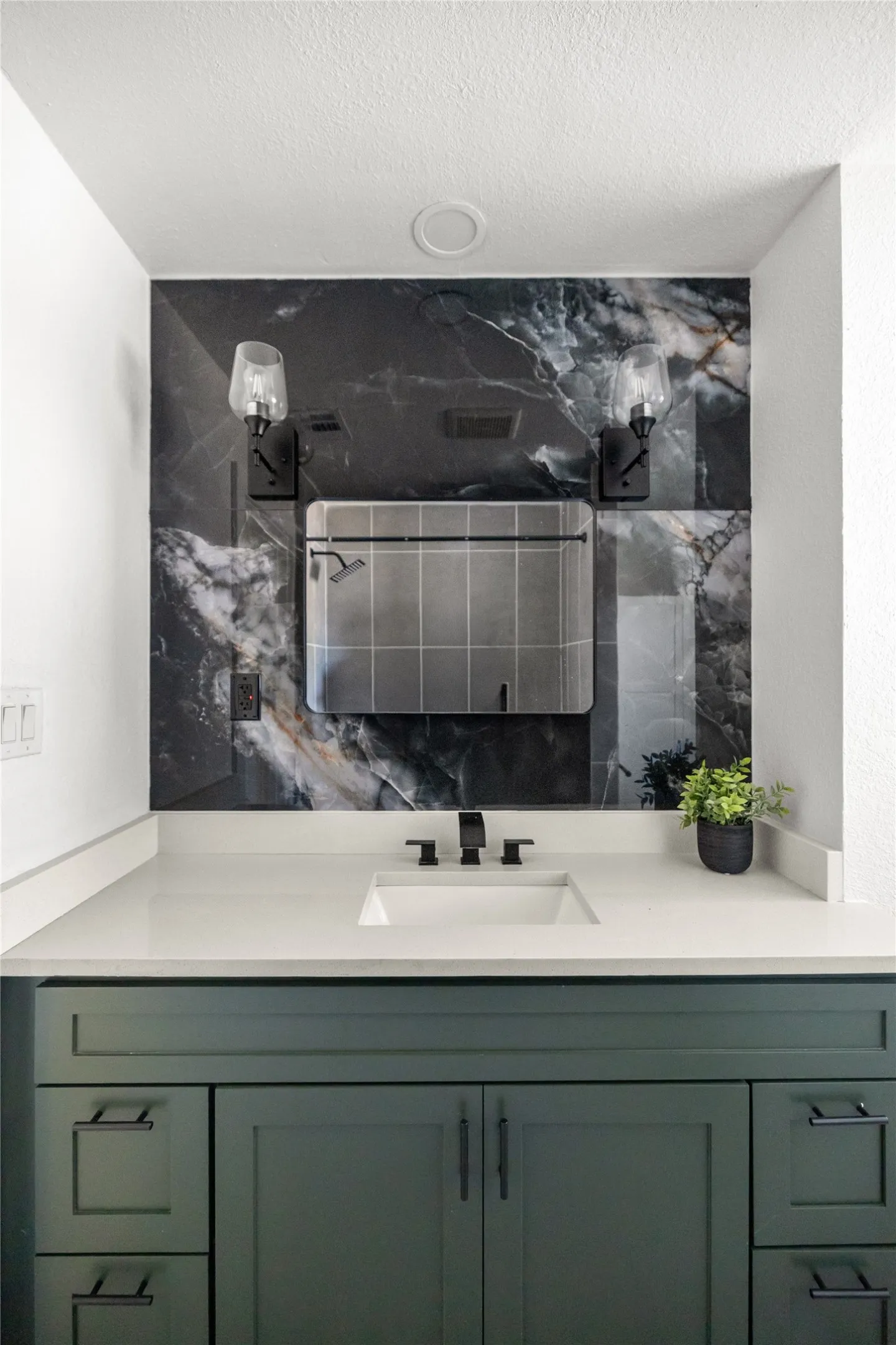 Vanity with a light-toned countertop, integrated sink, and dark-toned faucet