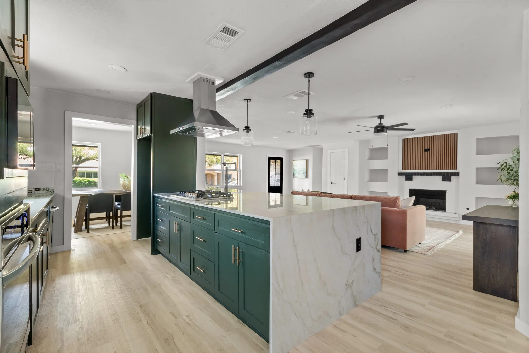 Kitchen island with waterfall countertop, dark green cabinetry, stainless steel range hood, wood-finish flooring, and recessed lighting
