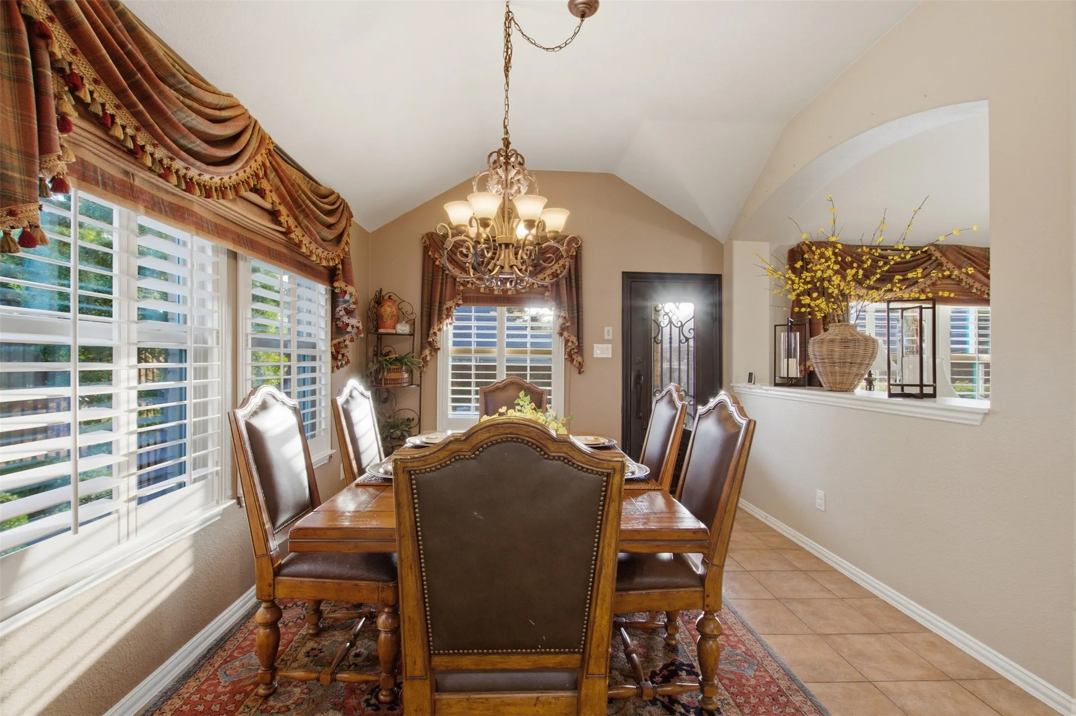 Formal dining area featuring vaulted ceilings, tile flooring, and decorative chandelier