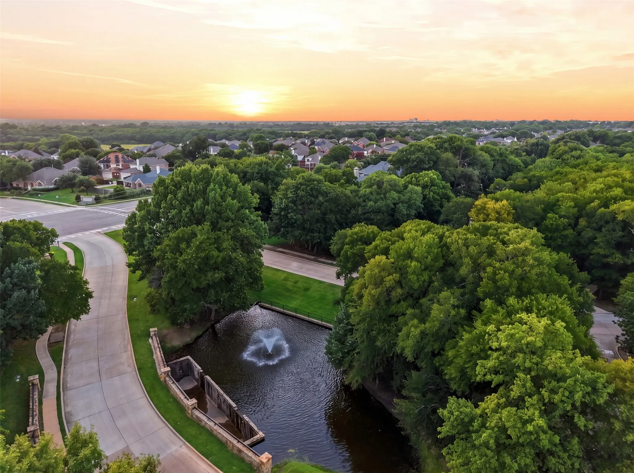 Expansive tree-lined neighborhood with a water feature, fountain, and paved roads