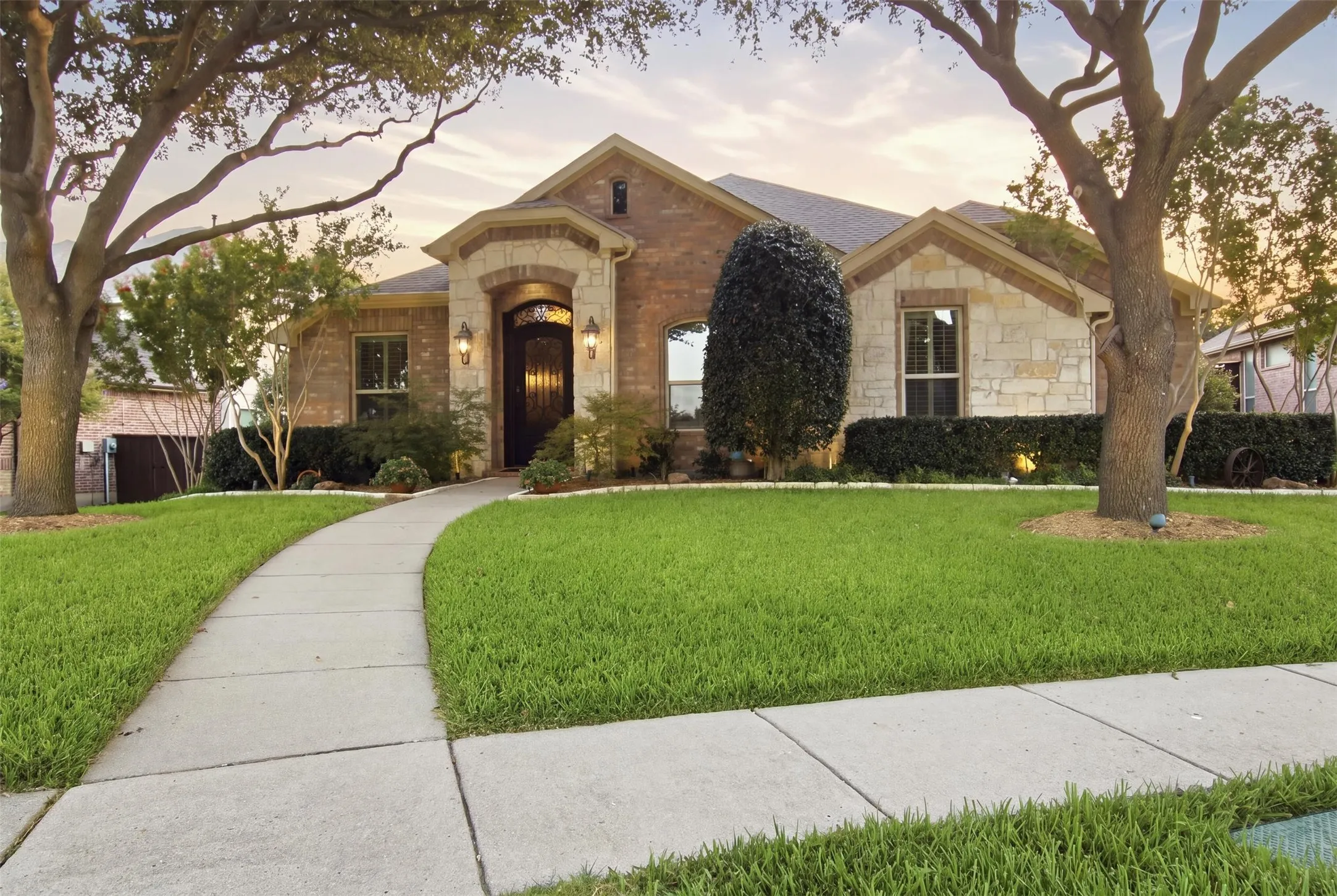 Stone and brick facade with an arched entry, prominent front door, and a curved sidewalk