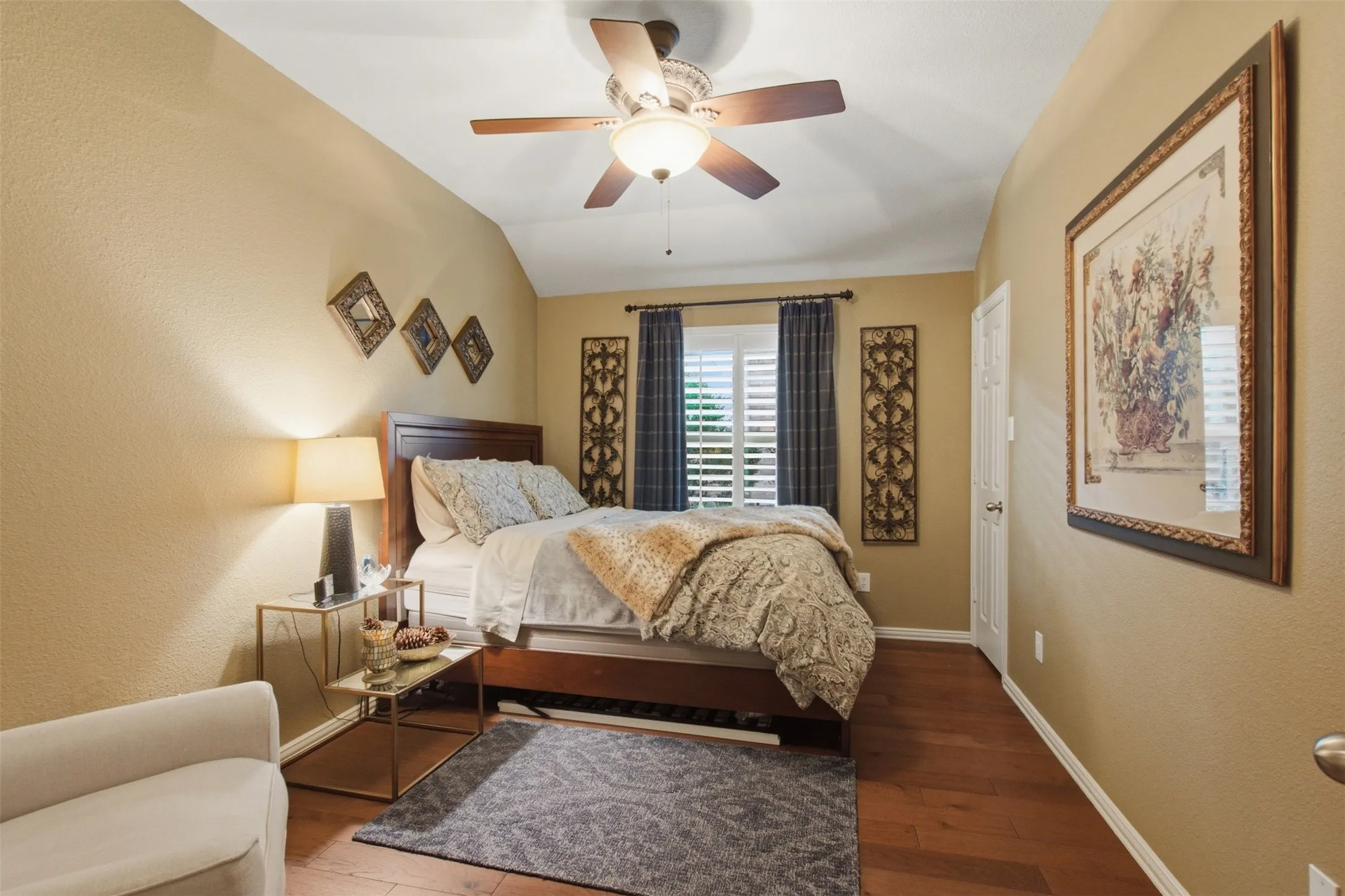 Vaulted ceiling with a ceiling fan, wood-finish flooring, plantation shutters, and a paneled door