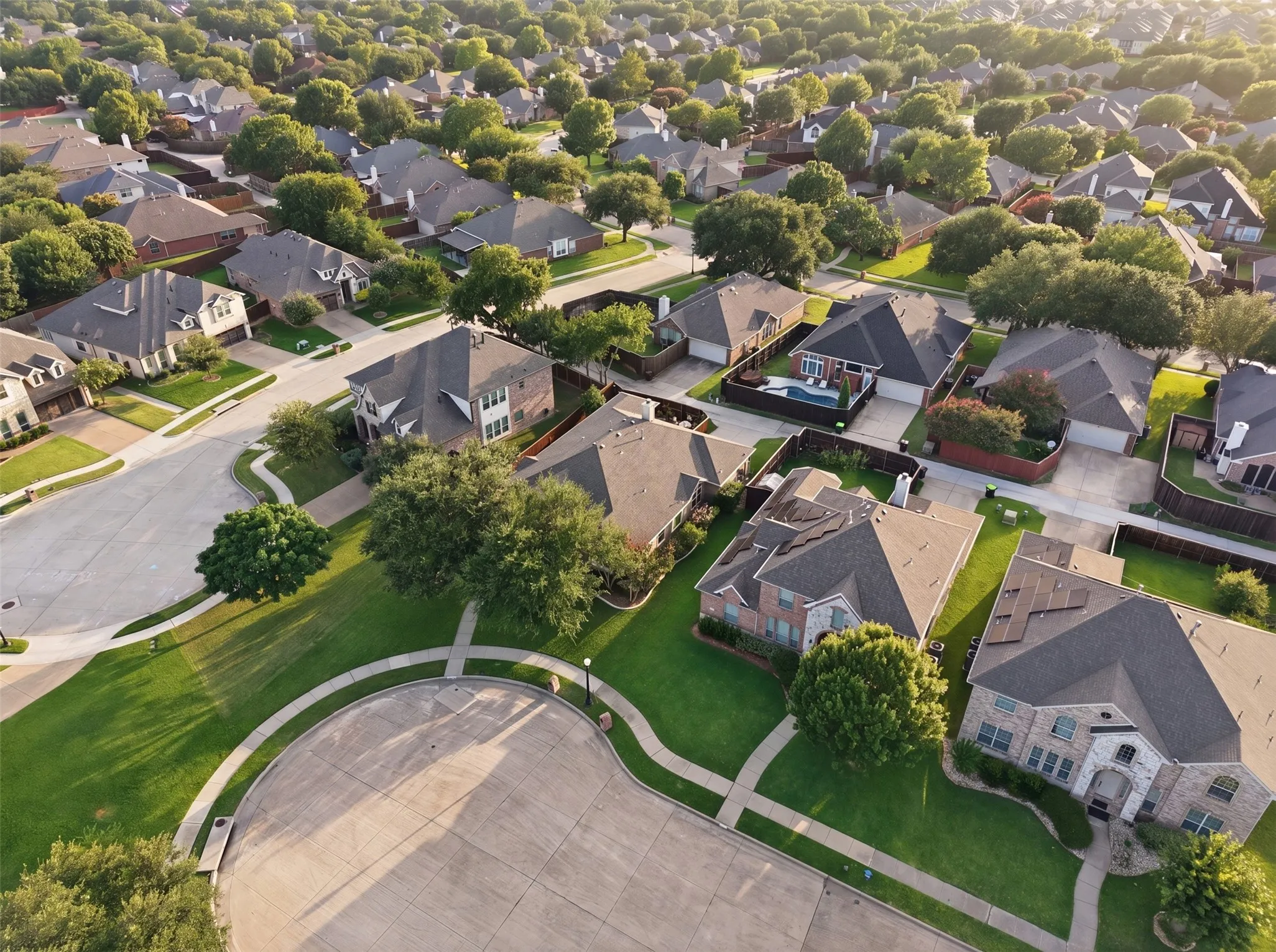 Residential neighborhood featuring single-family homes, mature trees, concrete streets, and landscaped yards