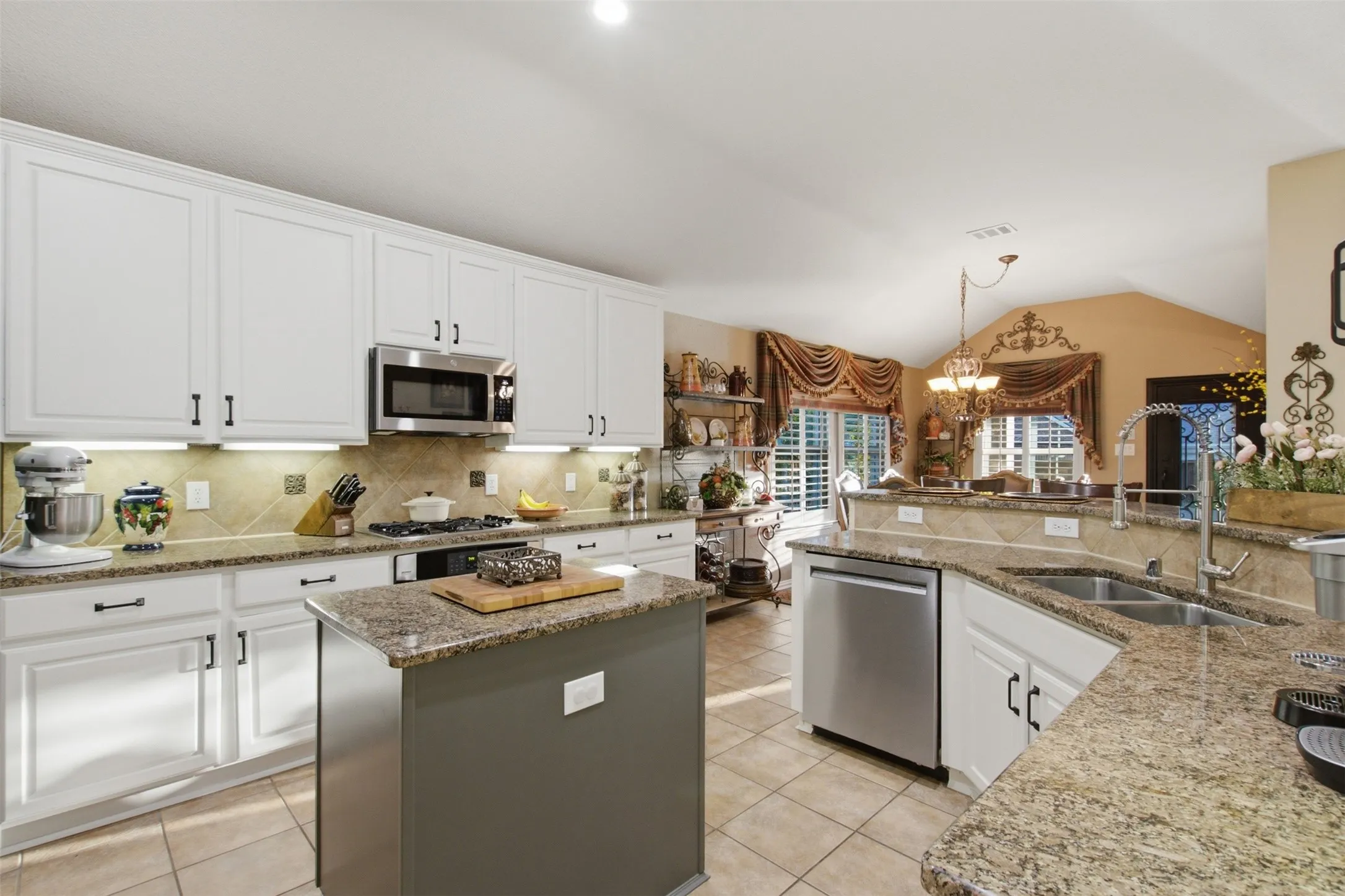 White cabinetry, stainless steel appliances, granite countertops, tile backsplash, and a central island