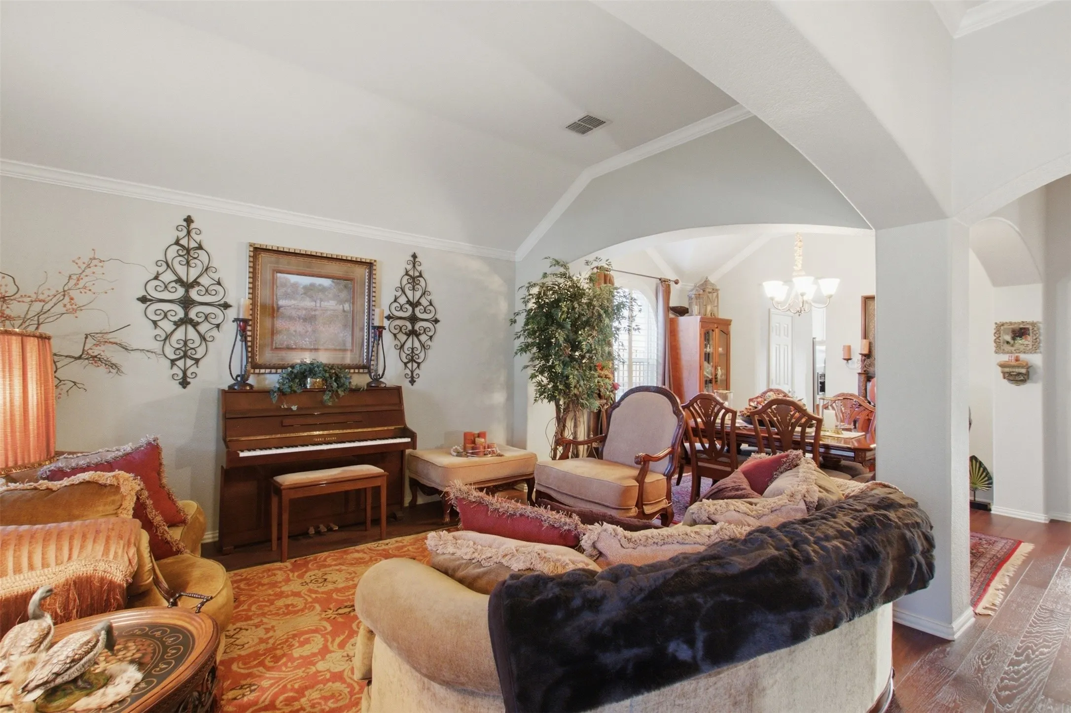Vaulted ceiling, crown molding, wood-finish flooring, arched doorways, and recessed lighting