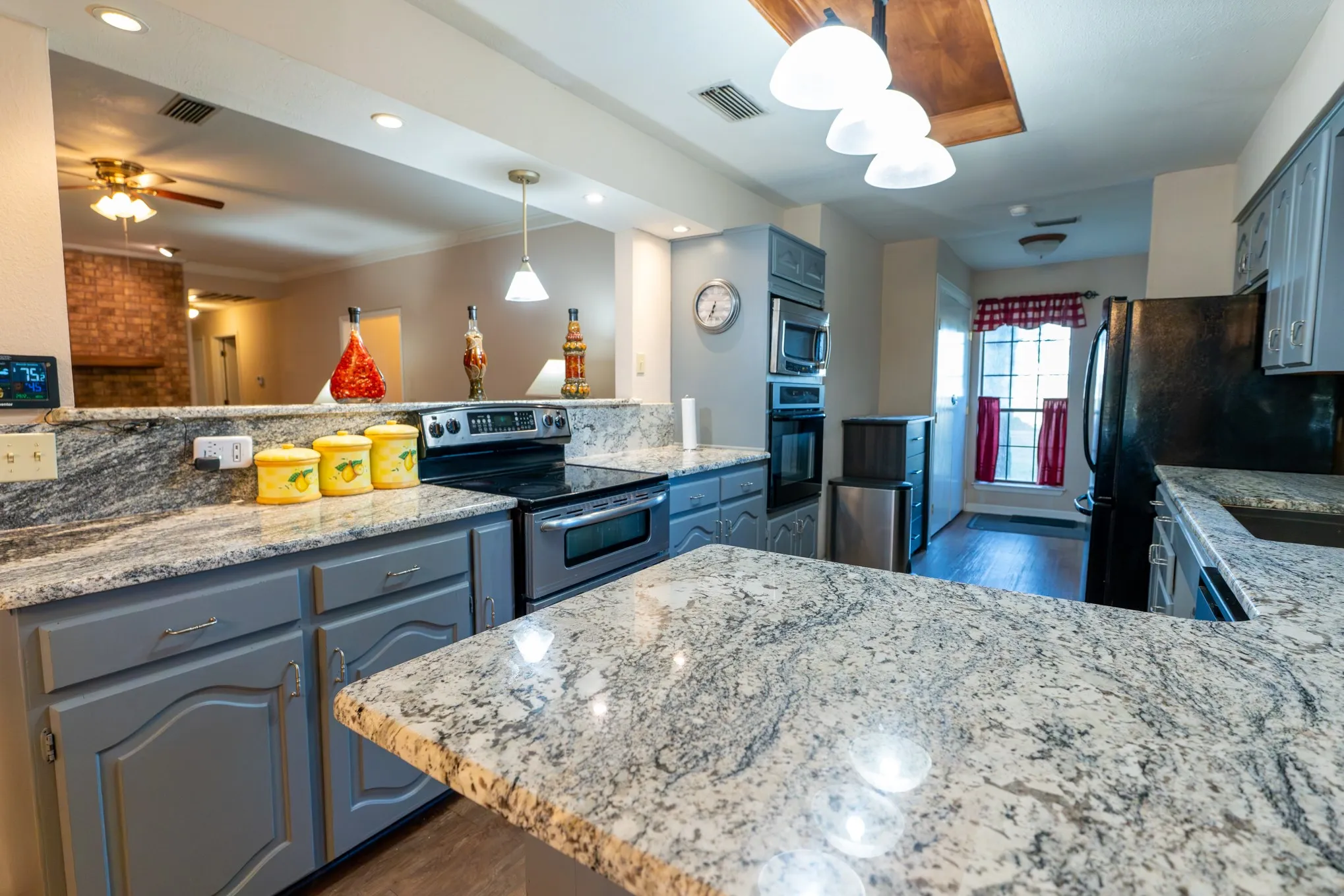 Expansive kitchen featuring stone countertops, built-in stainless steel appliances, and grey cabinetry