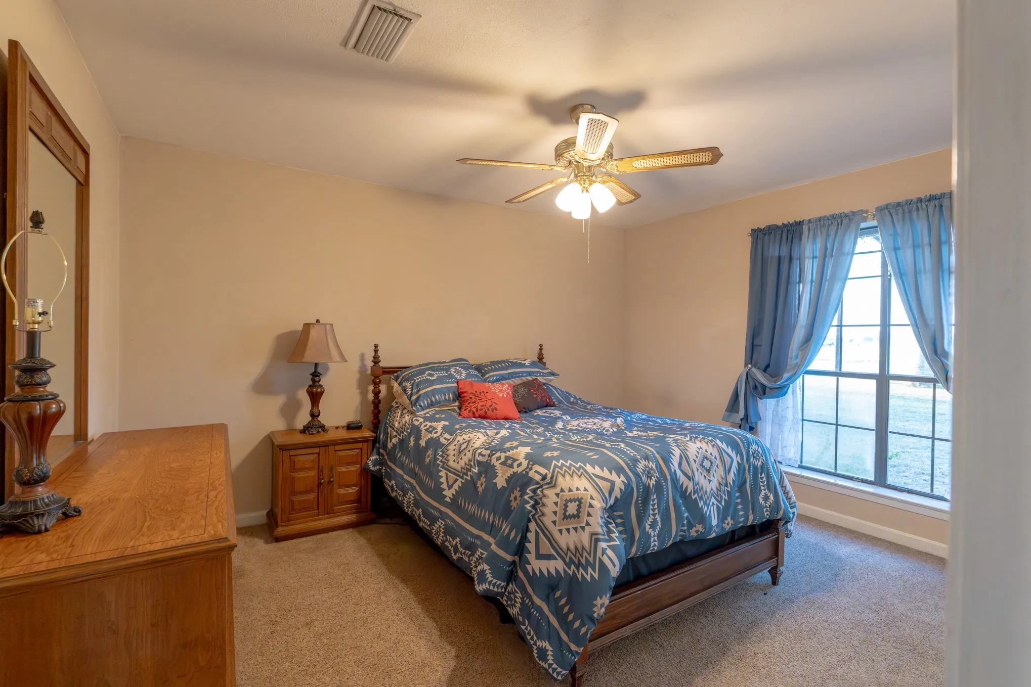 Carpeted flooring, ceiling fan with light fixture, and a window with vertical mullions