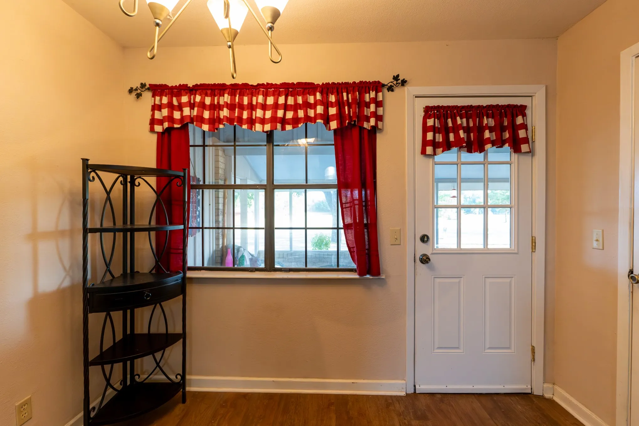 Wood-finish flooring, white paneled door with window, and a multi-pane window