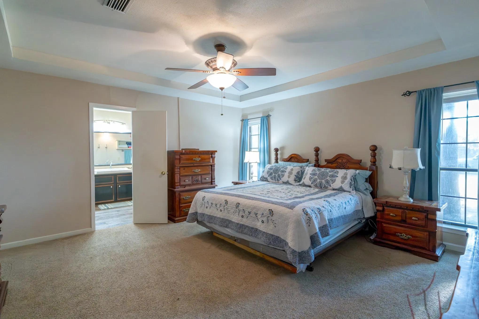 Carpeted interior with a tray ceiling and ceiling fan