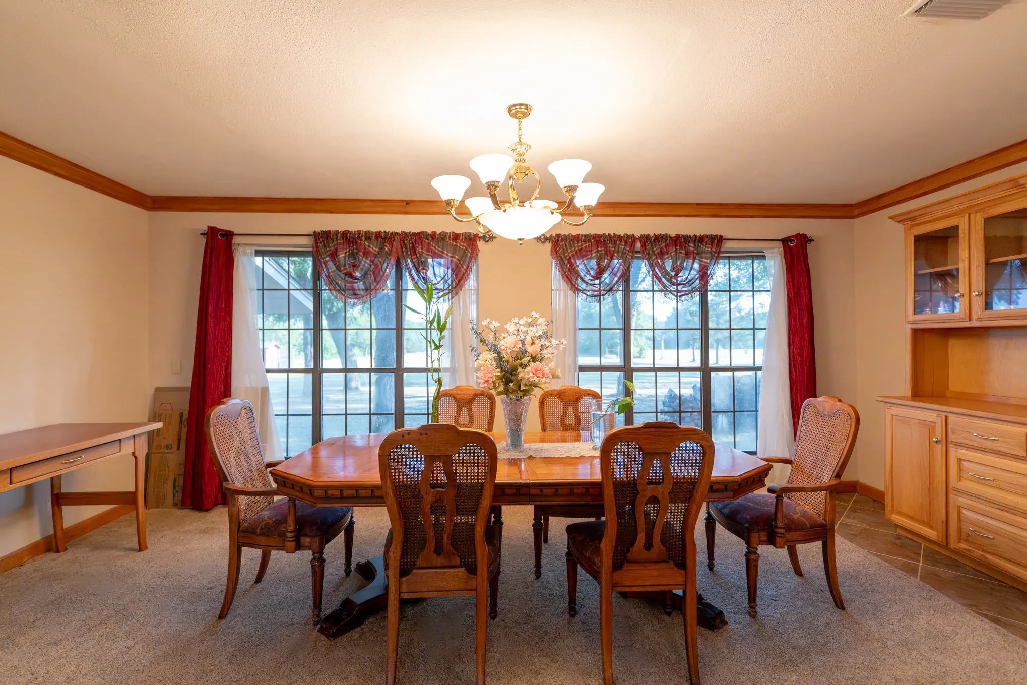 Recessed lighting and a multi-arm chandelier illuminate the room
