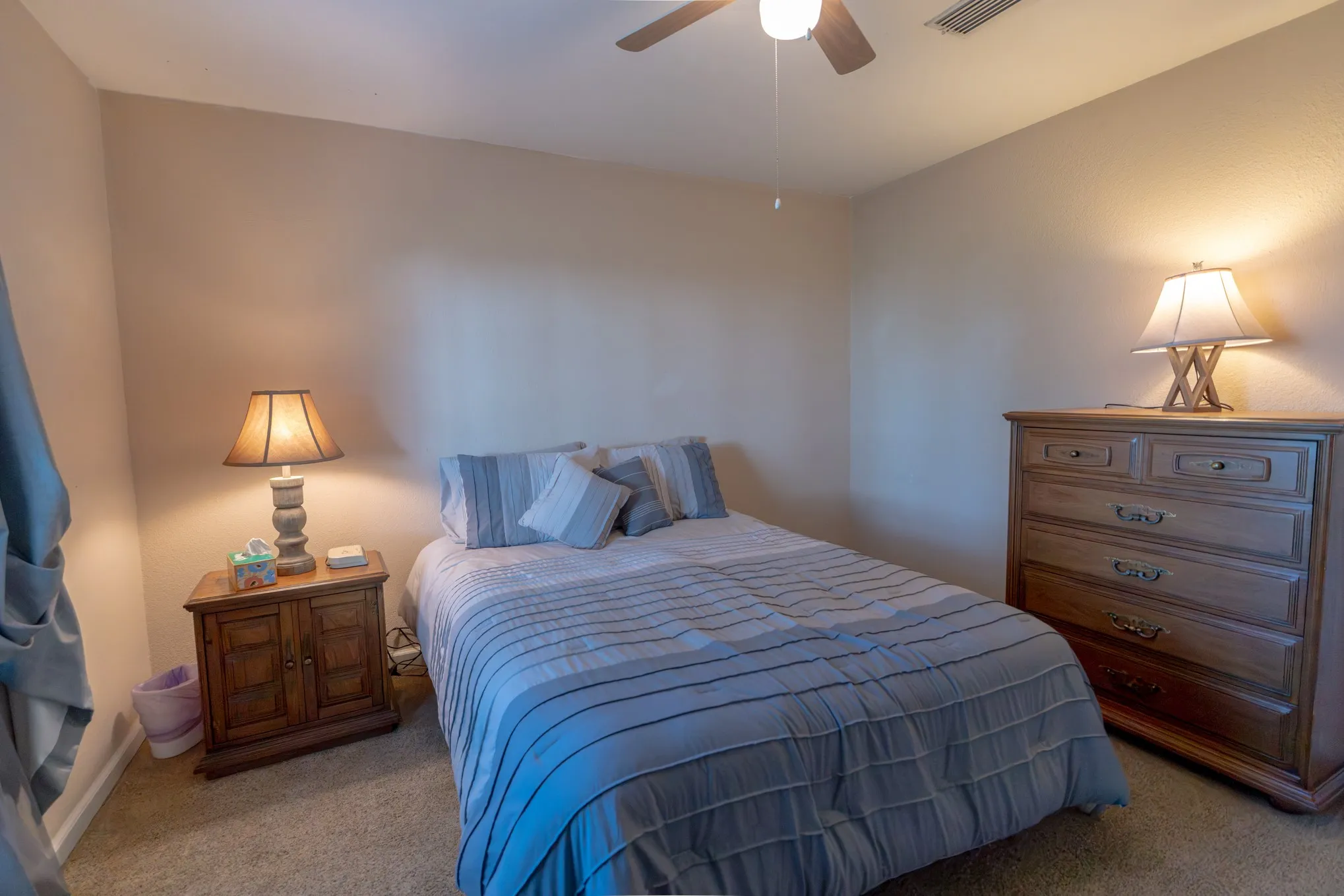 Neutral-toned wall paint, textured carpeting, and a ceiling fan with integrated lighting