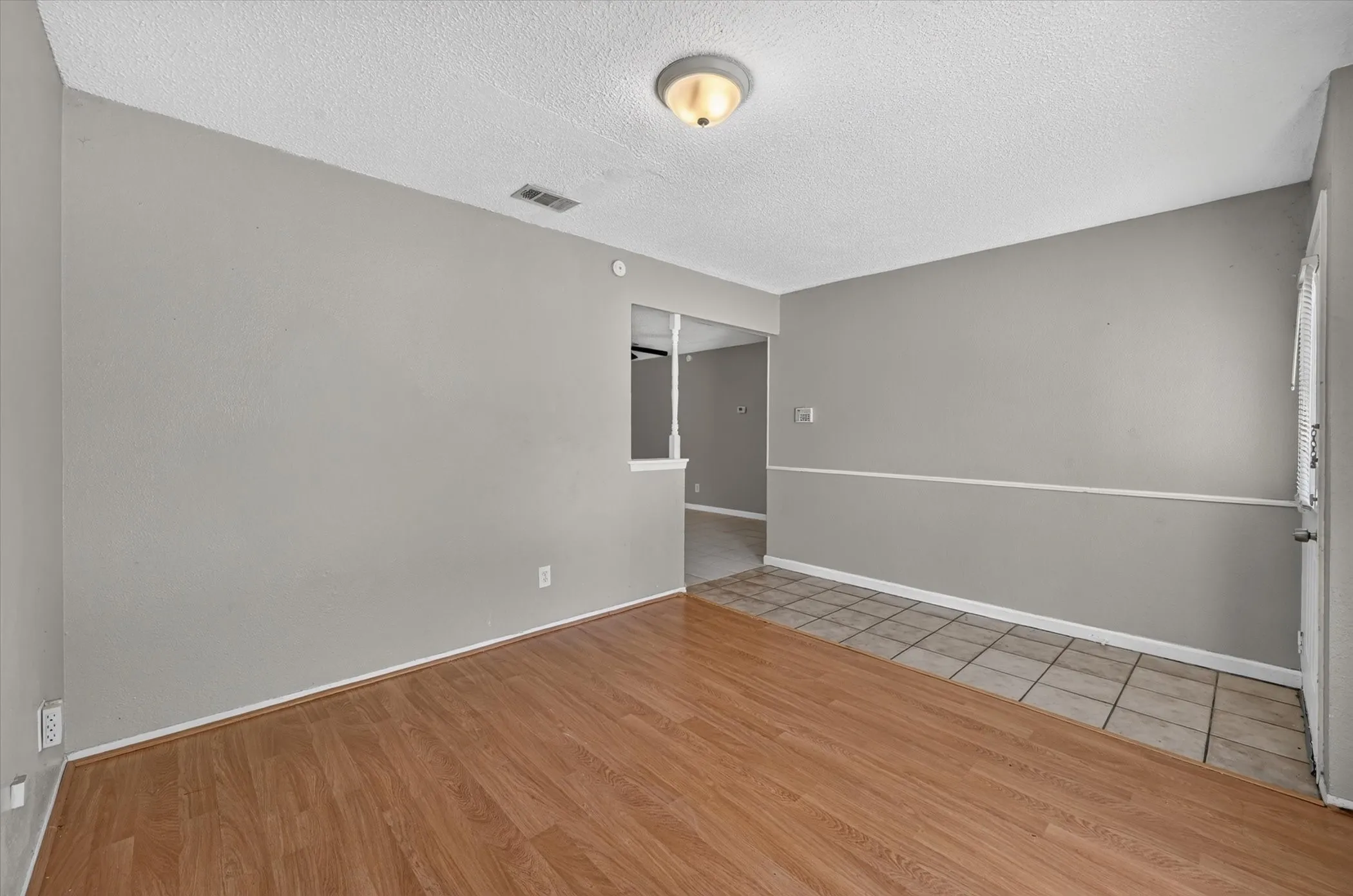 A versatile front room with durable laminate flooring, ideal for a home office, formal dining room, or flex space.