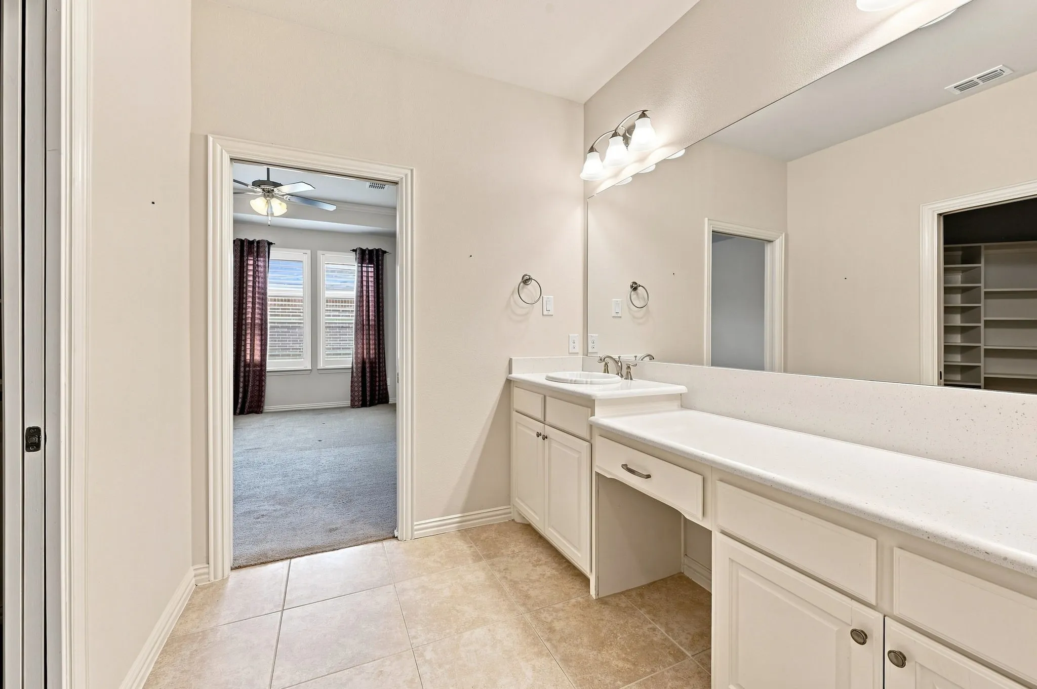 Dual vanity with integrated sinks, expansive counter space, white cabinetry, and a large wall-mounted mirror