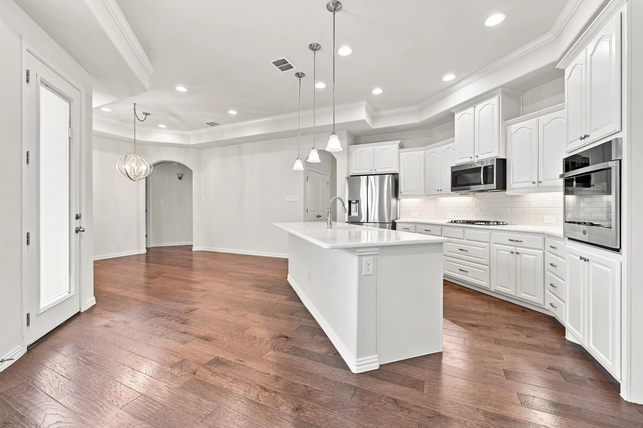 Expansive wood-finish flooring, recessed lighting, and a tray ceiling