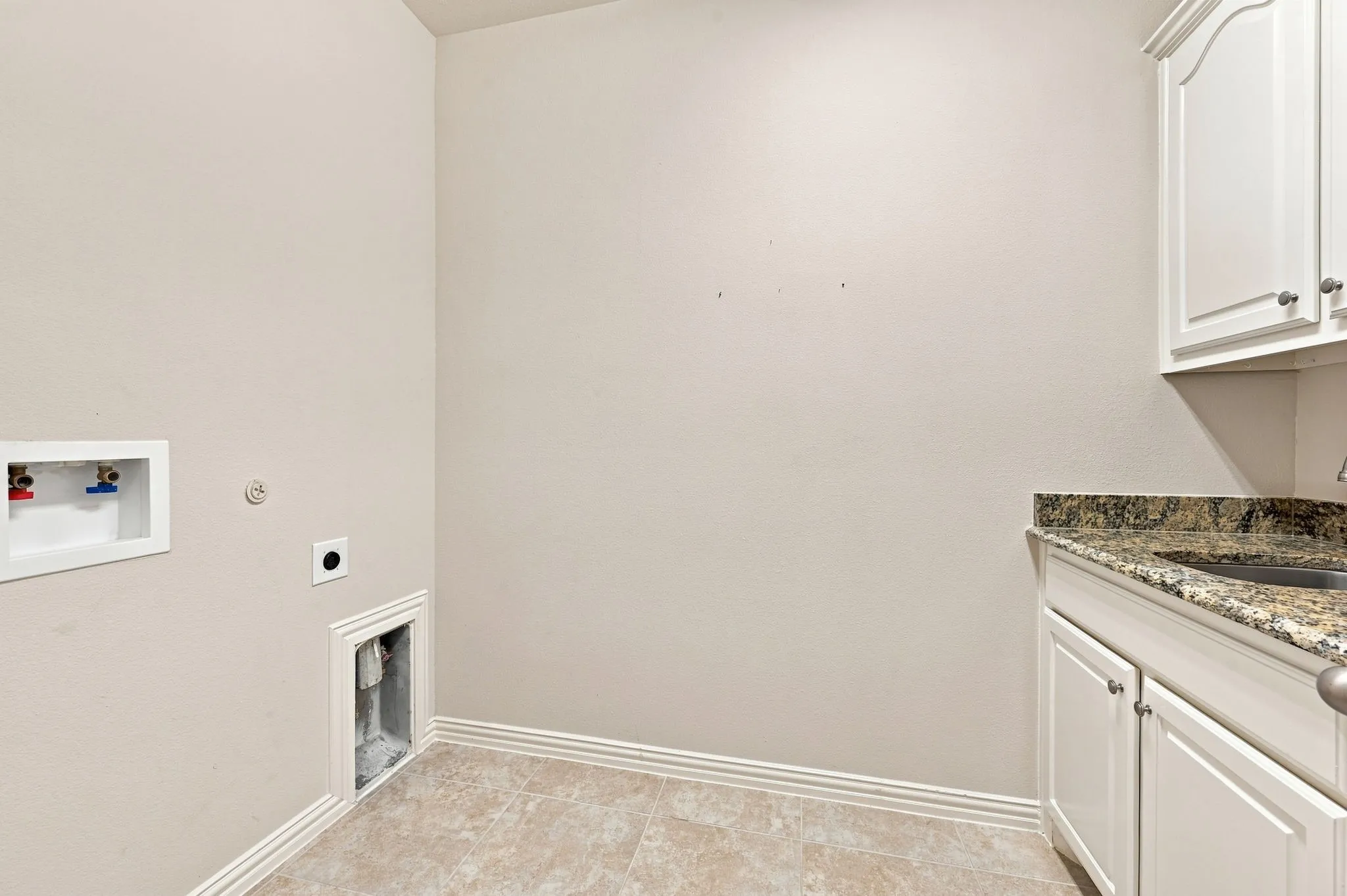 Utility area with built-in cabinetry, stone countertop, integrated sink, and tile flooring