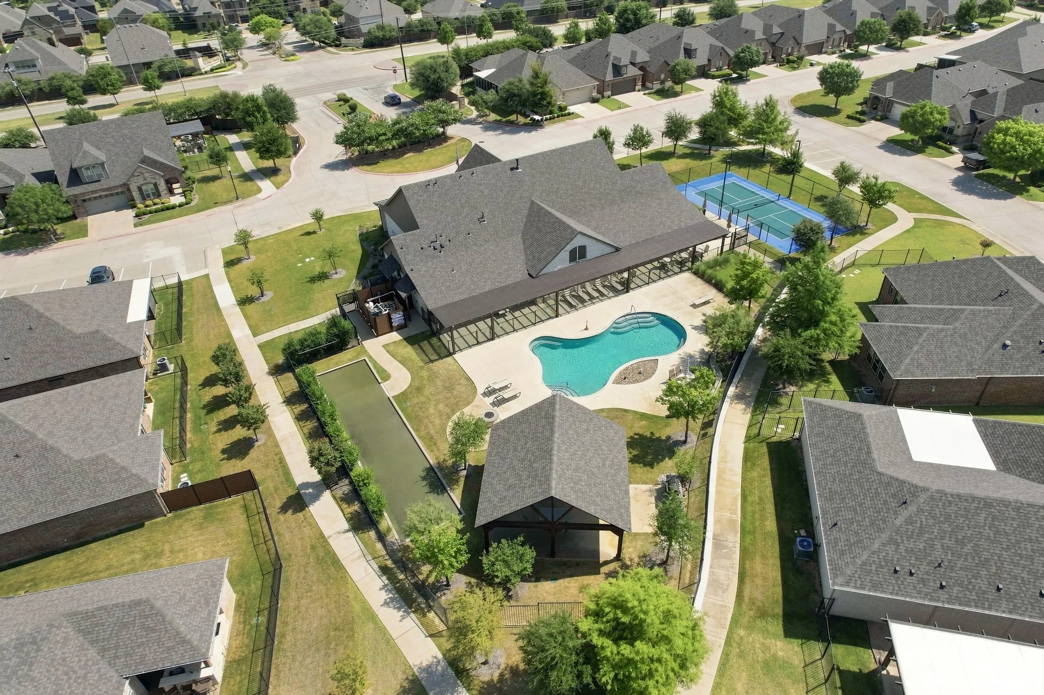 Community amenities featuring a swimming pool, covered outdoor lounge areas, tennis court, and bocce ball court