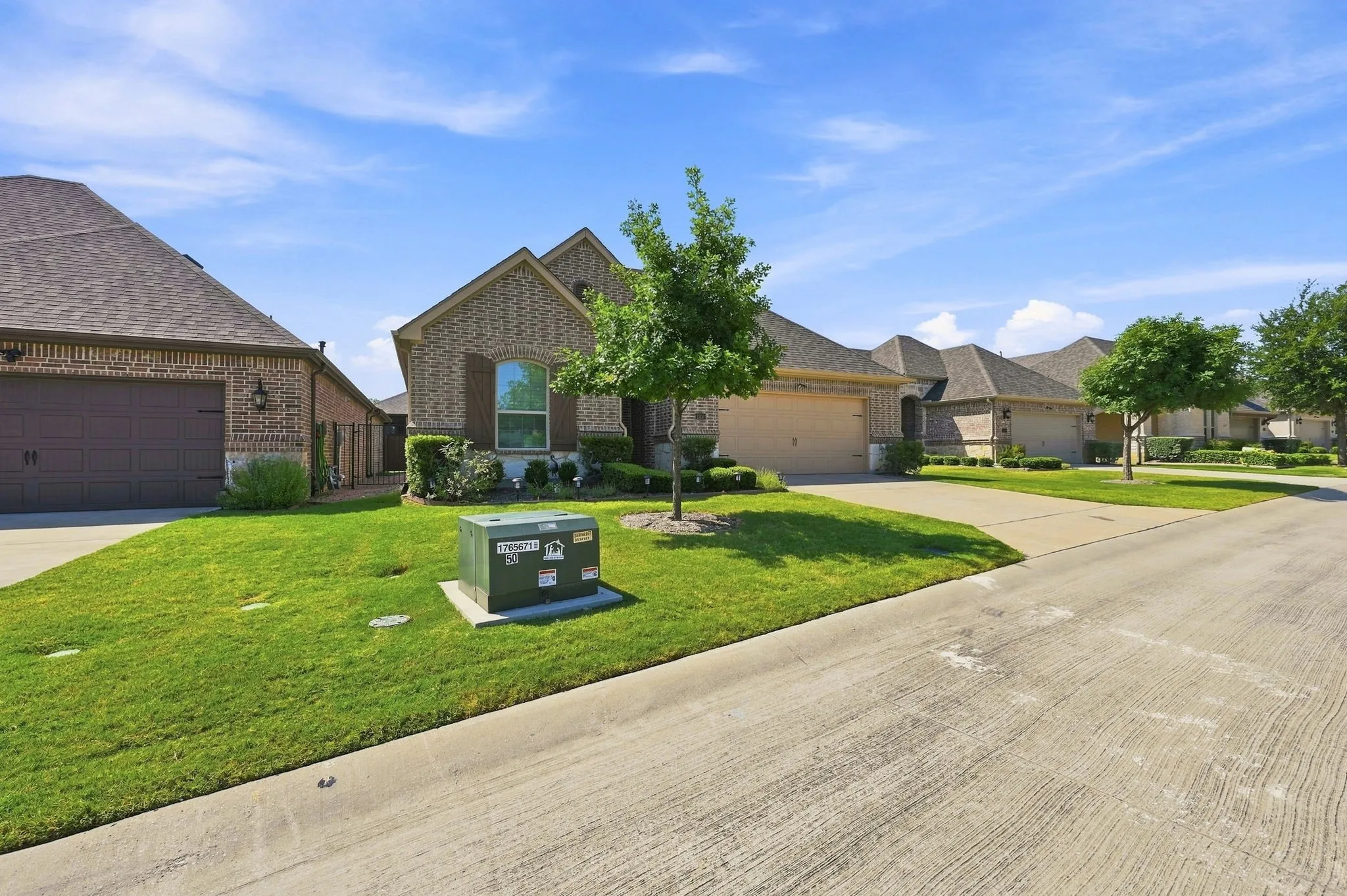 Brick exterior residence with an attached garage, landscaped lawn, and concrete driveway