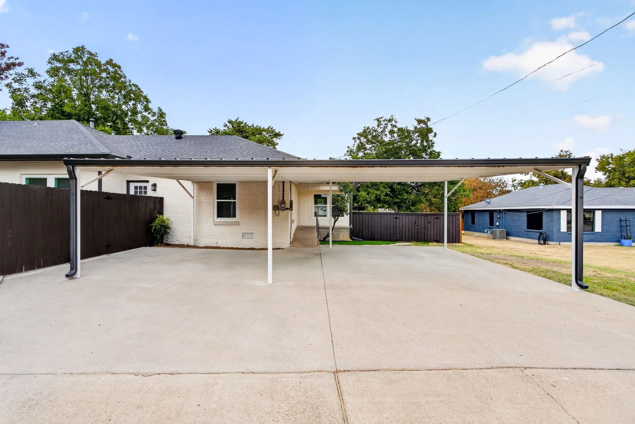 Huge carport with ramp leading up to the home. Gate on left leads to the side yard just shown.