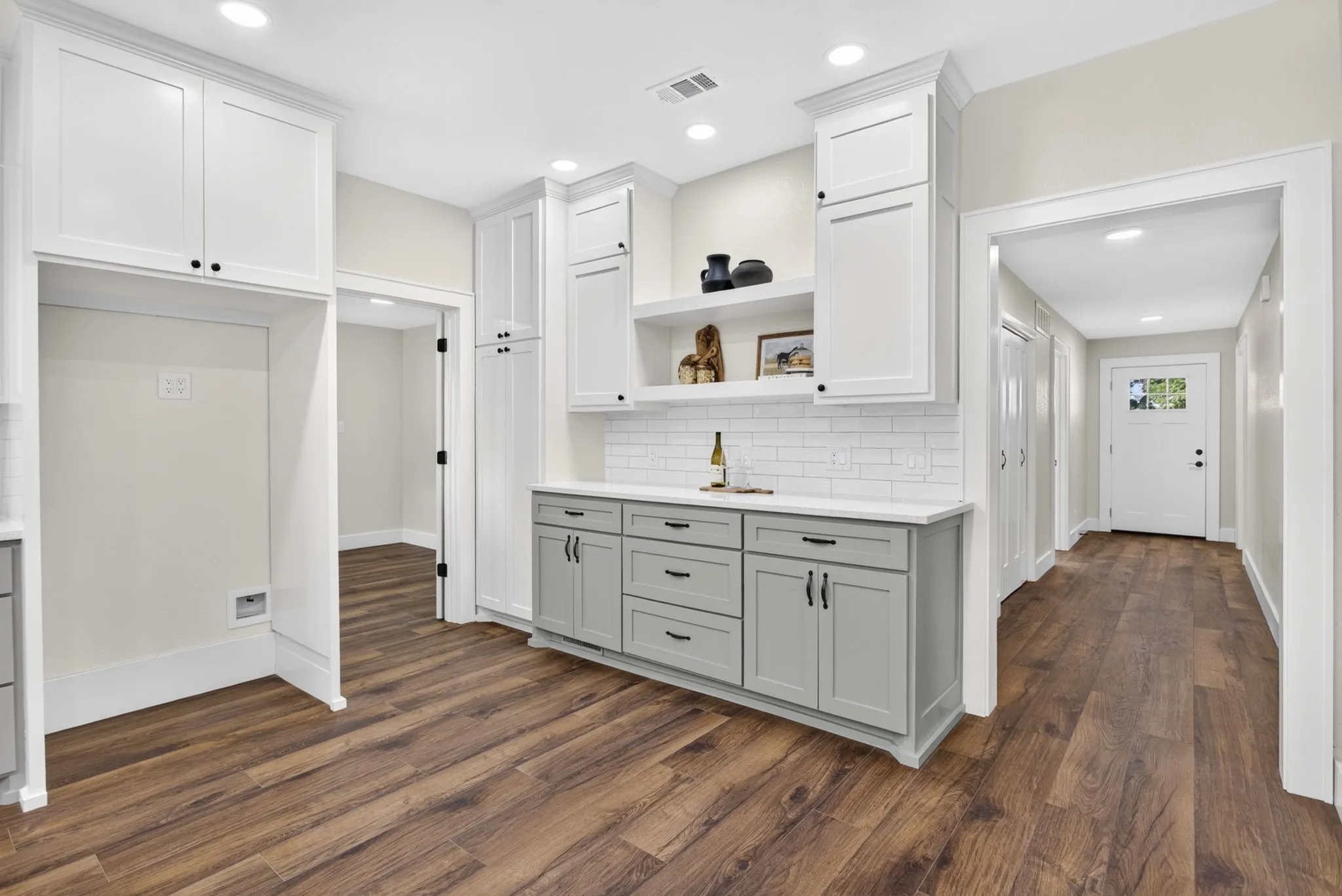 Every opportunity for storage and value was utilized - including this fabulous coffee bar with broom cabinet. Hallway leads to primary and guest suite. Laundry room to the left.