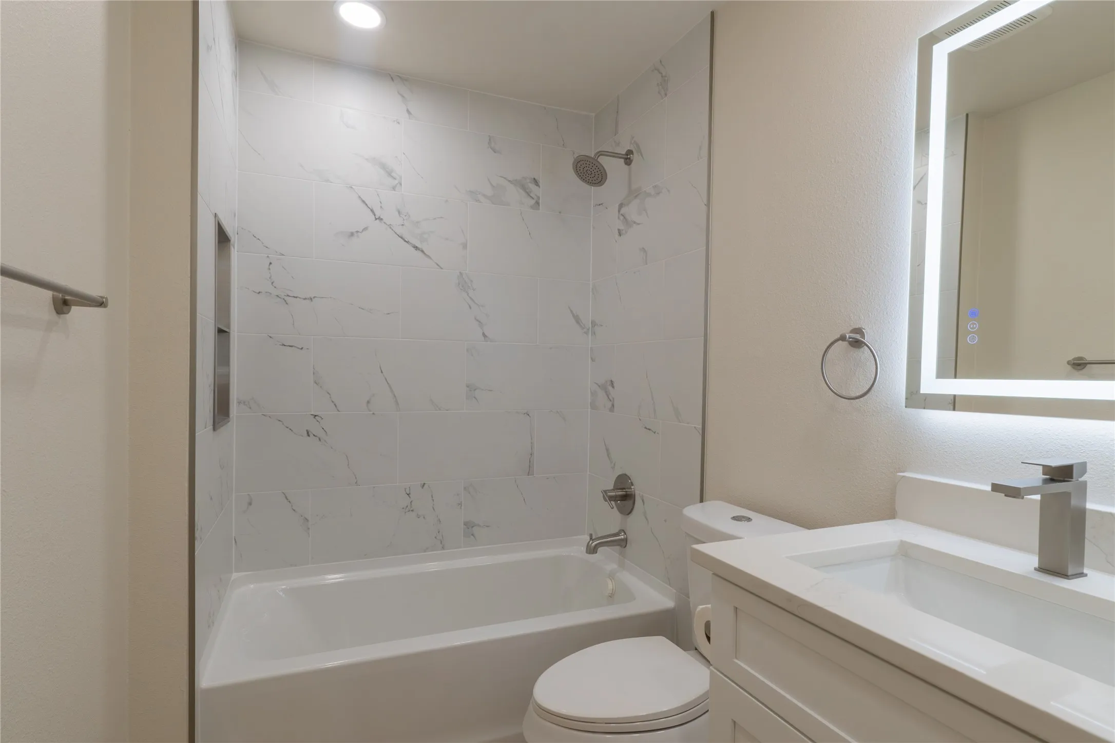 Bathtub with white subway tile surround and integrated shower niche