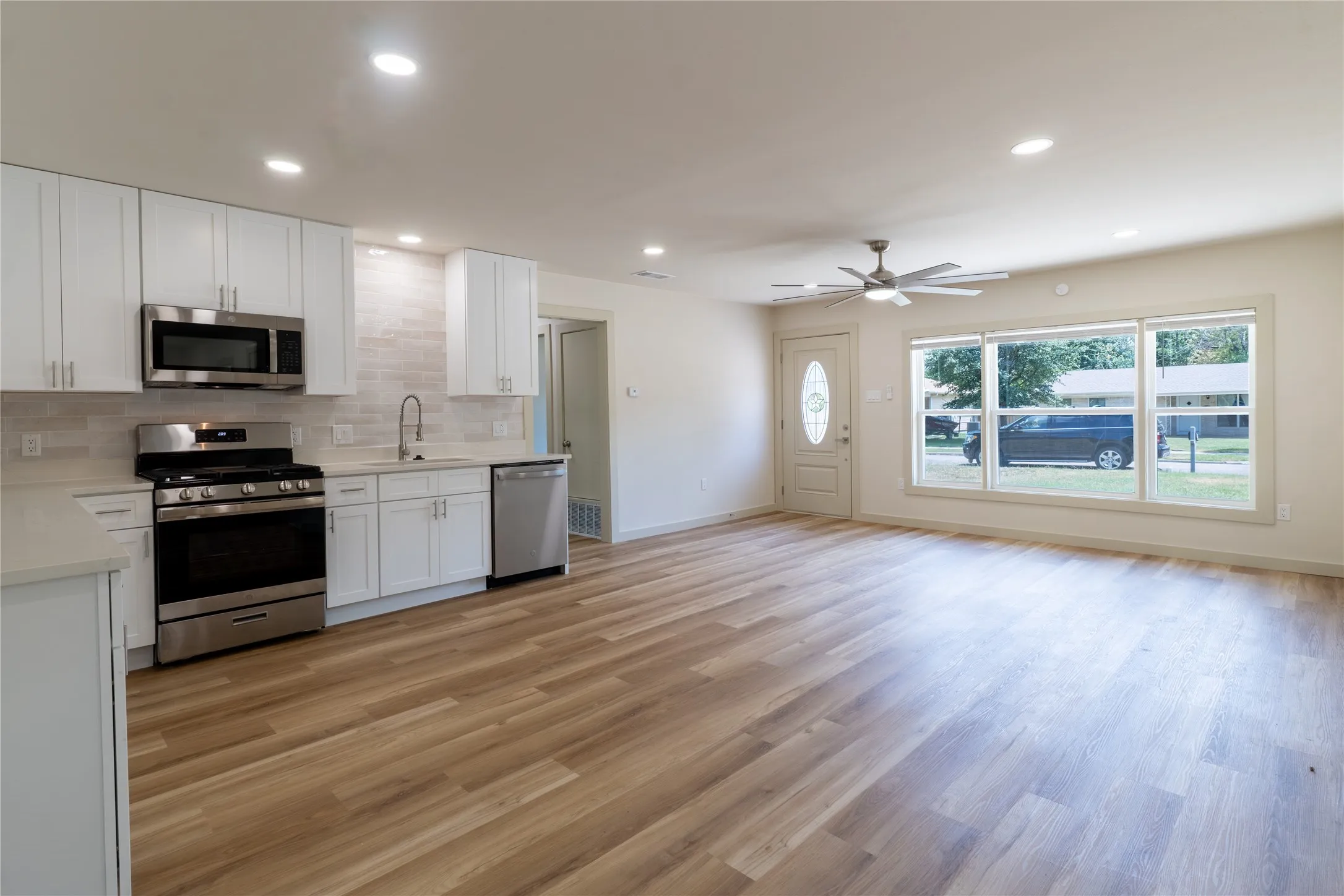 Open-concept living space with wood-finish flooring, recessed lighting, and a ceiling fan