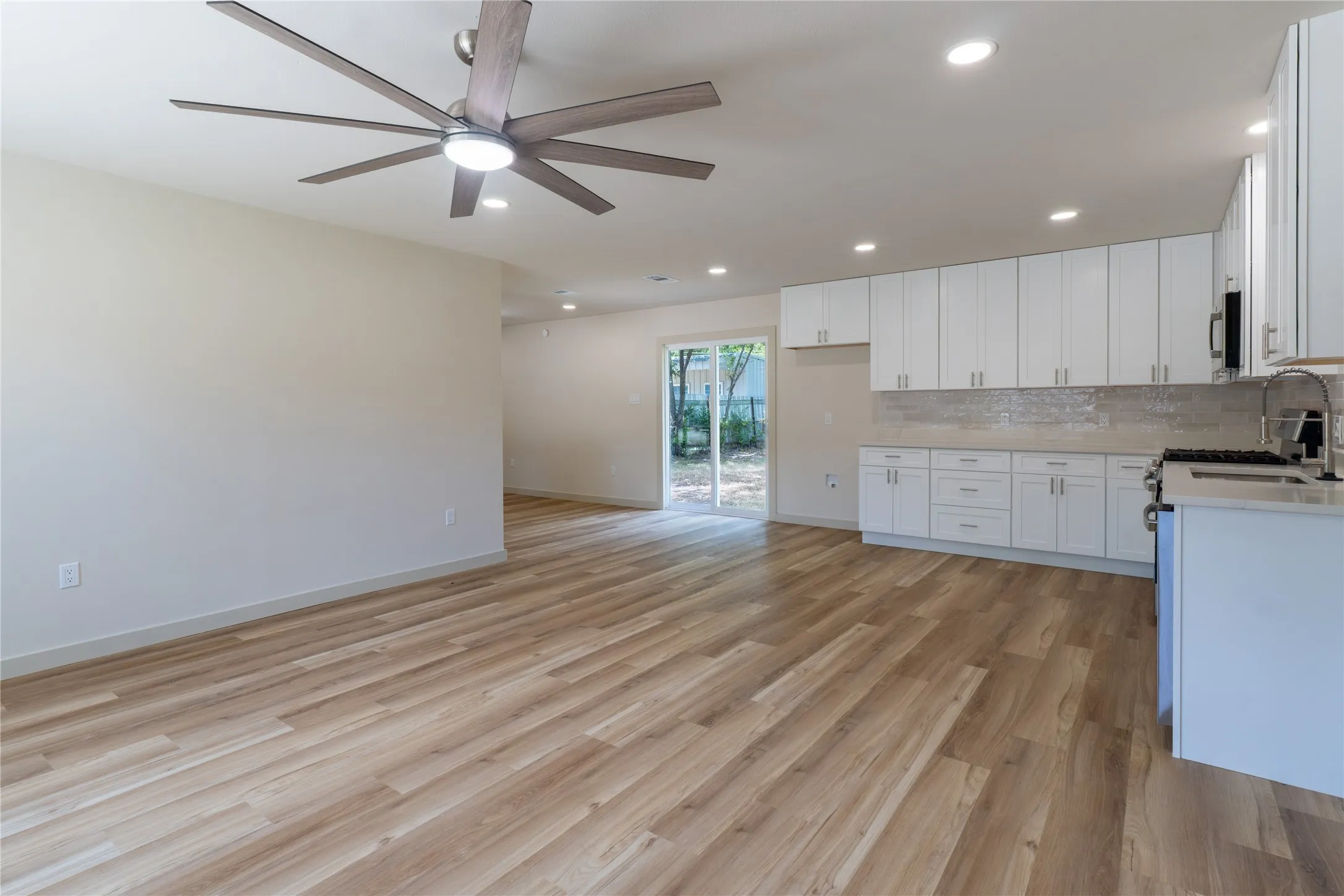 Open-concept living area with wood-finish flooring, recessed lighting, and a contemporary ceiling fan