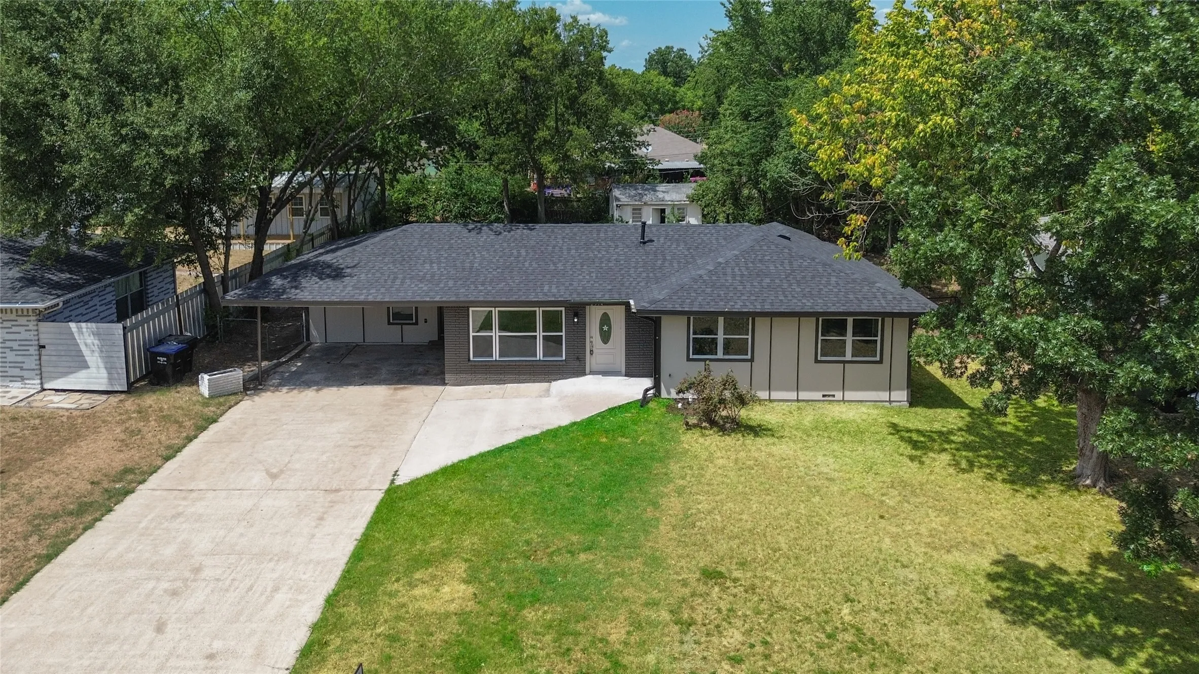 Single-story residence featuring a dark shingle roof, light-colored siding, and a concrete driveway