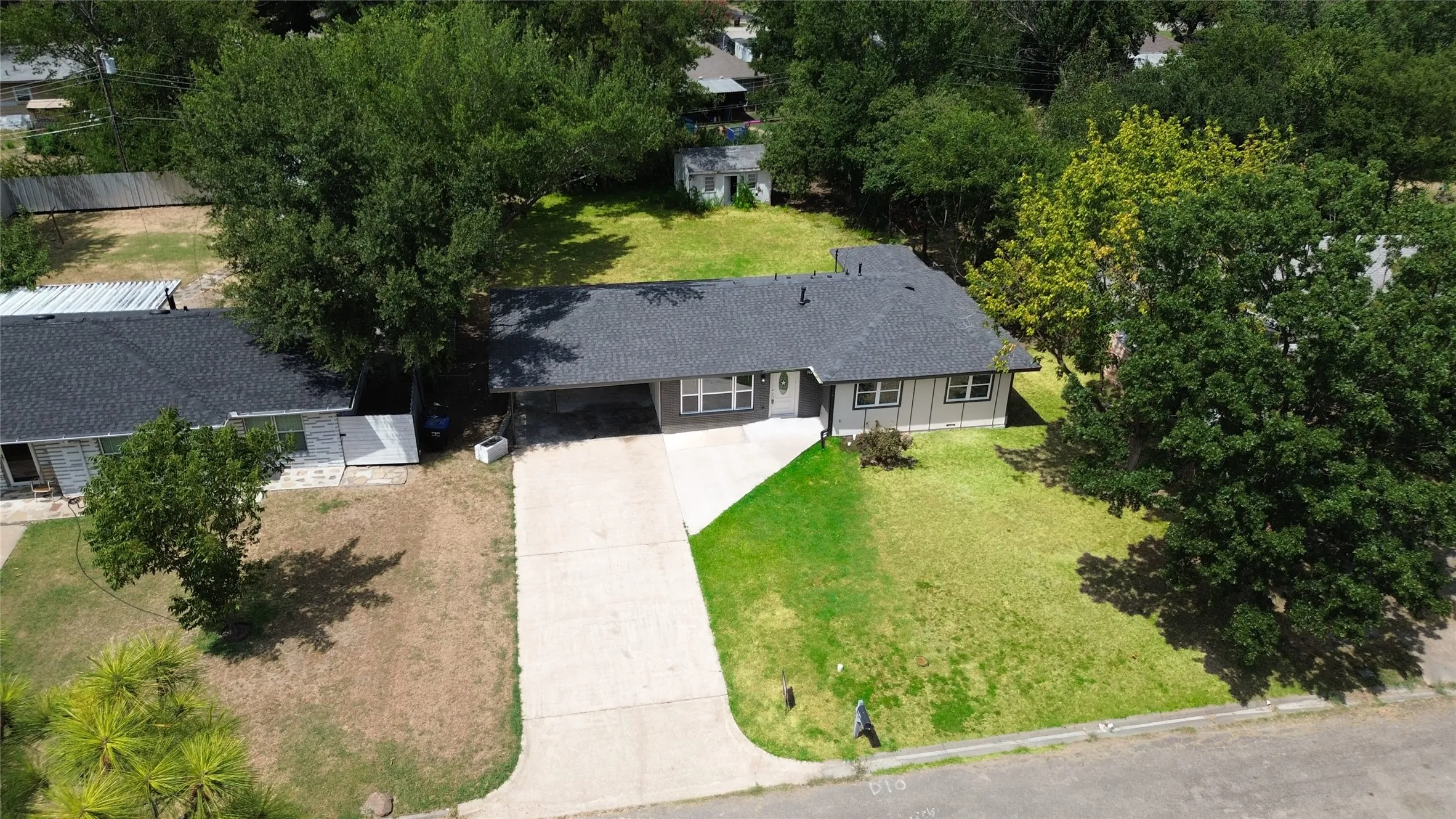 Single-story residence with a dark shingle roof, attached carport, and a concrete driveway