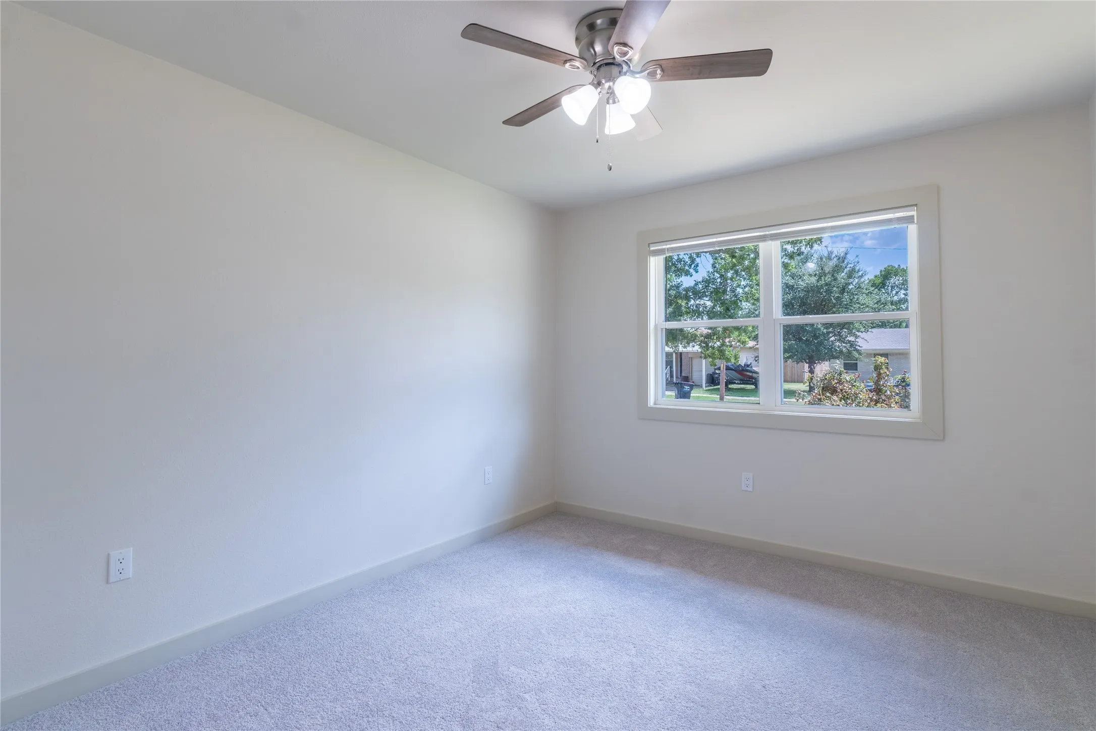 Recessed window with white trim, ceiling fan with light fixture, light gray carpeting, and neutral wall finish