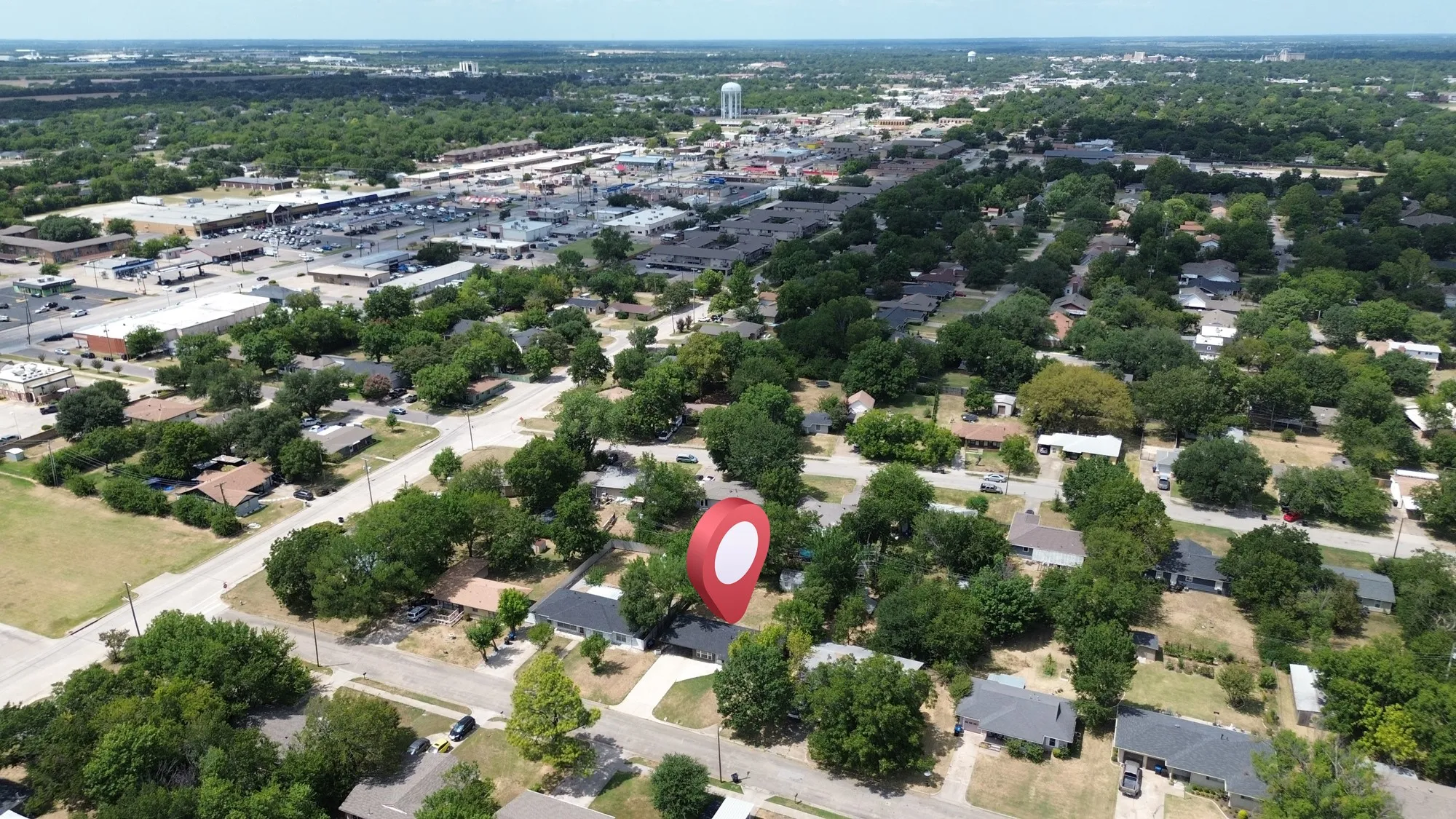 Residential neighborhood setting with mature trees and commercial developments in the background
