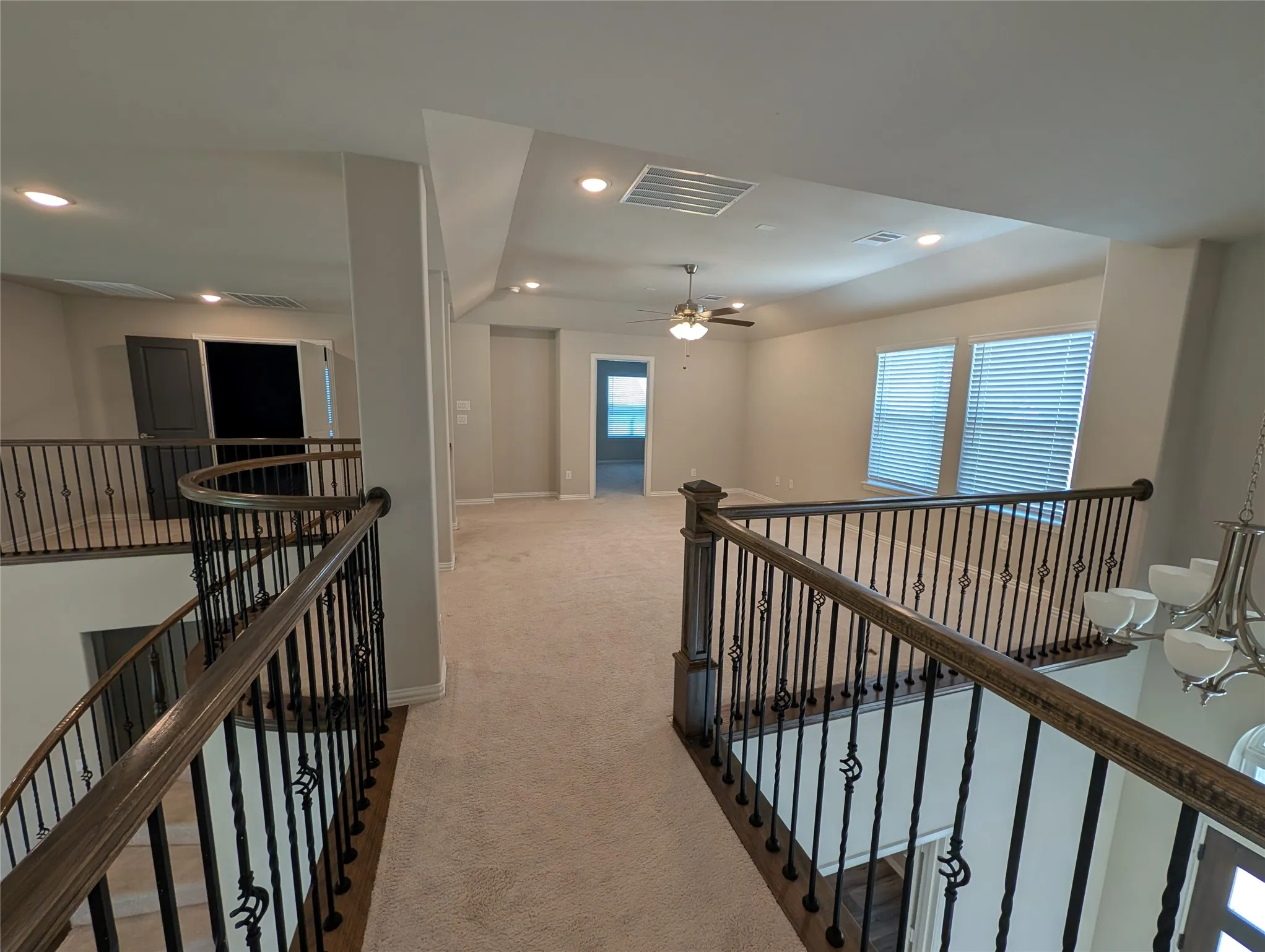 Expansive carpeted loft area with wrought iron balusters and wood handrails